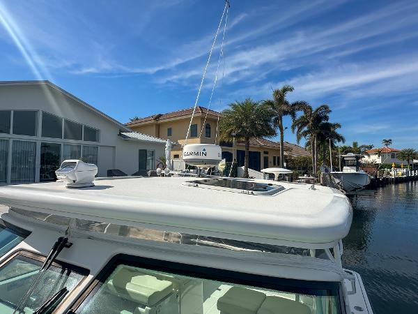 2006 Tiara Yachts 3200 Open docked near waterfront homes under a clear blue sky.