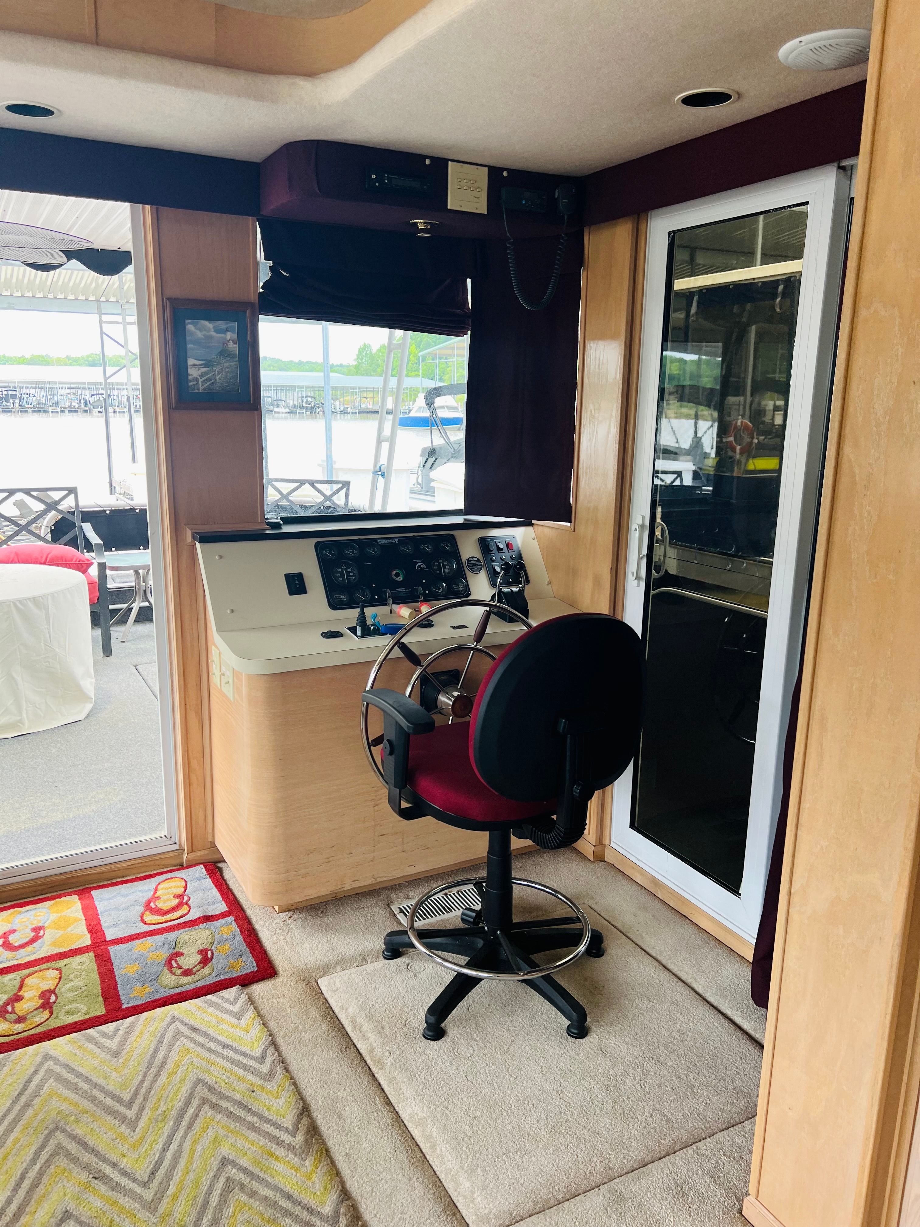 1998 Sumerset houseboat helm with steering wheel, control panel, and cushioned chair.