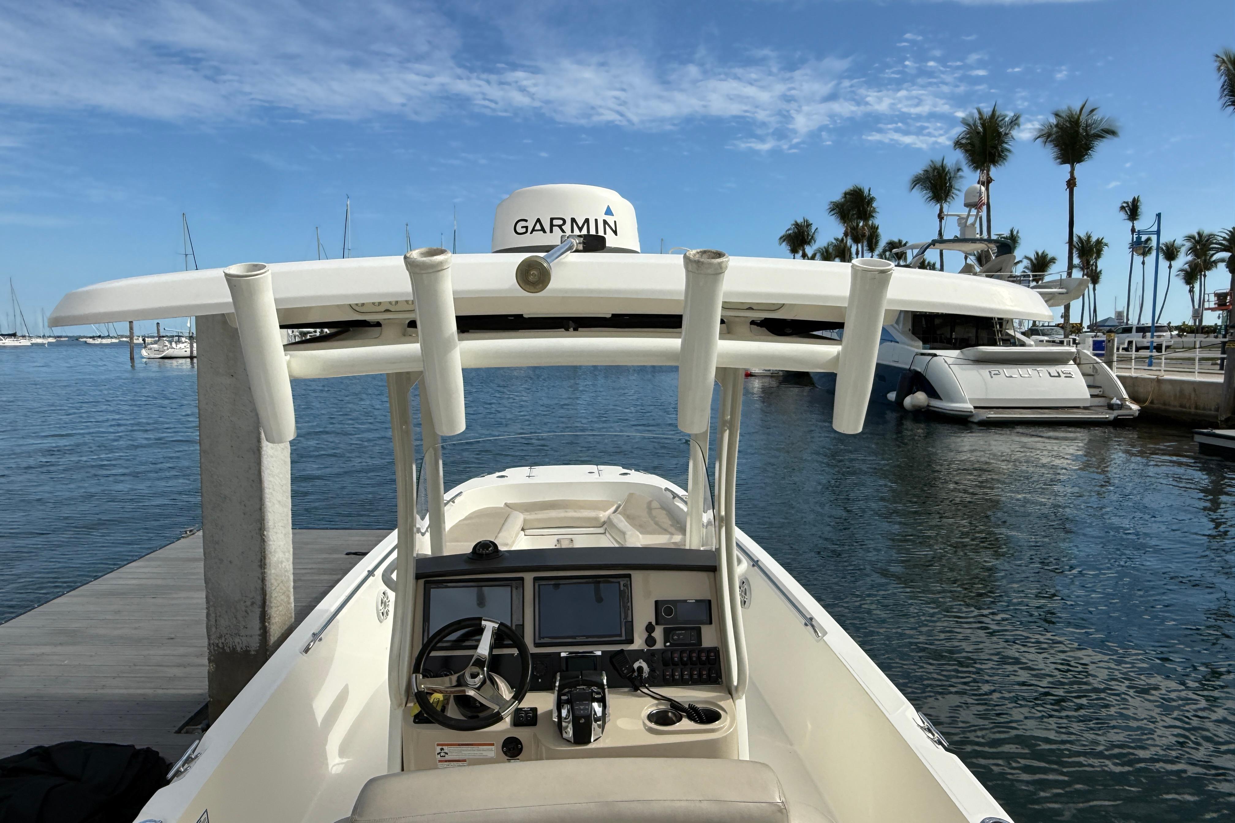 2018 Boston Whaler 270 Dauntless boat docked, featuring Garmin equipment, with palm trees in the background.