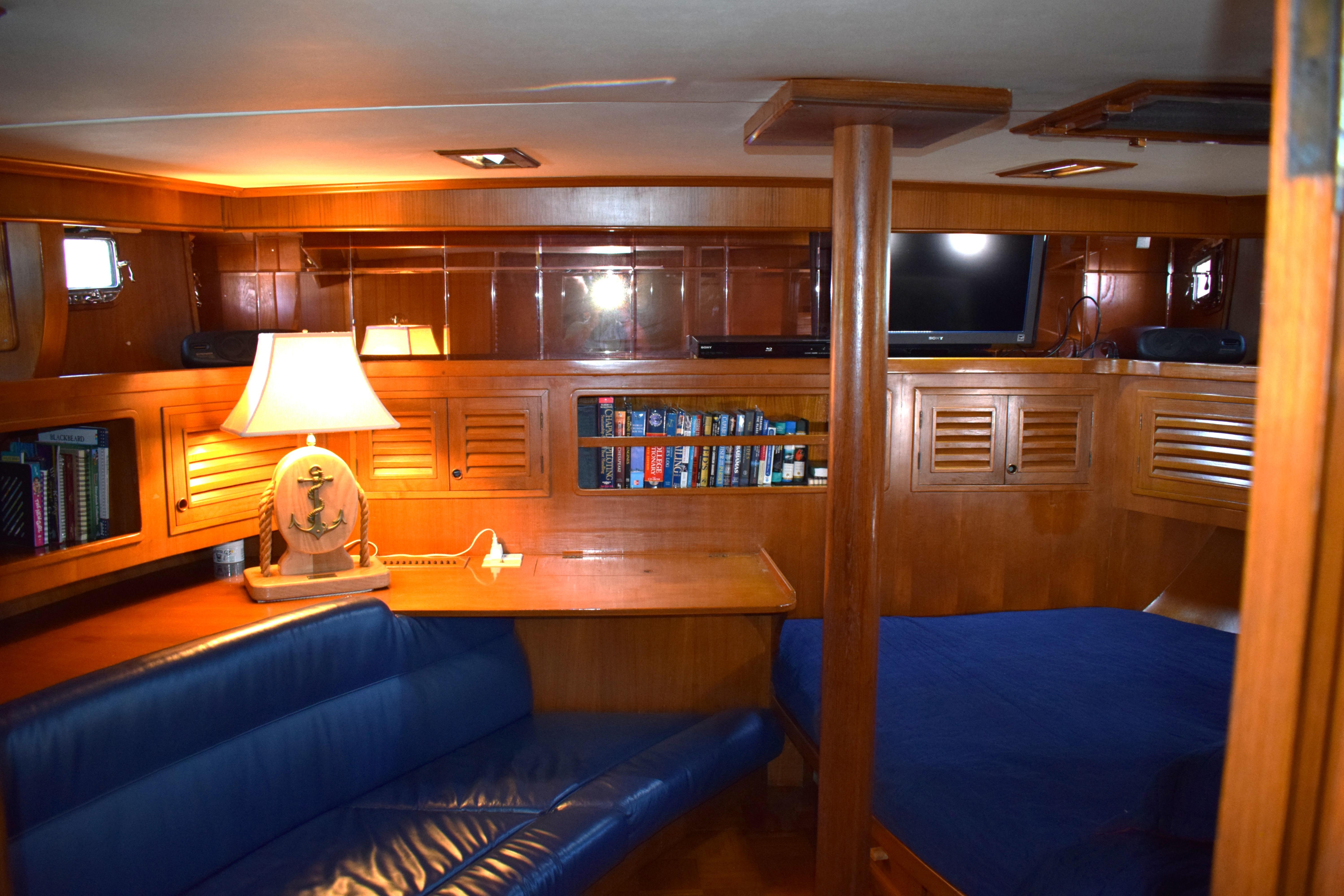 Interior of 1980 Cheoy Lee 52 Motorsailer with cozy seating, lamp, and bookshelf.