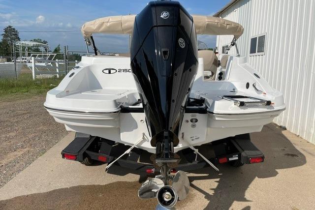 2026 Tahoe 2150 boat with powerful outboard motor, docked near a white building.