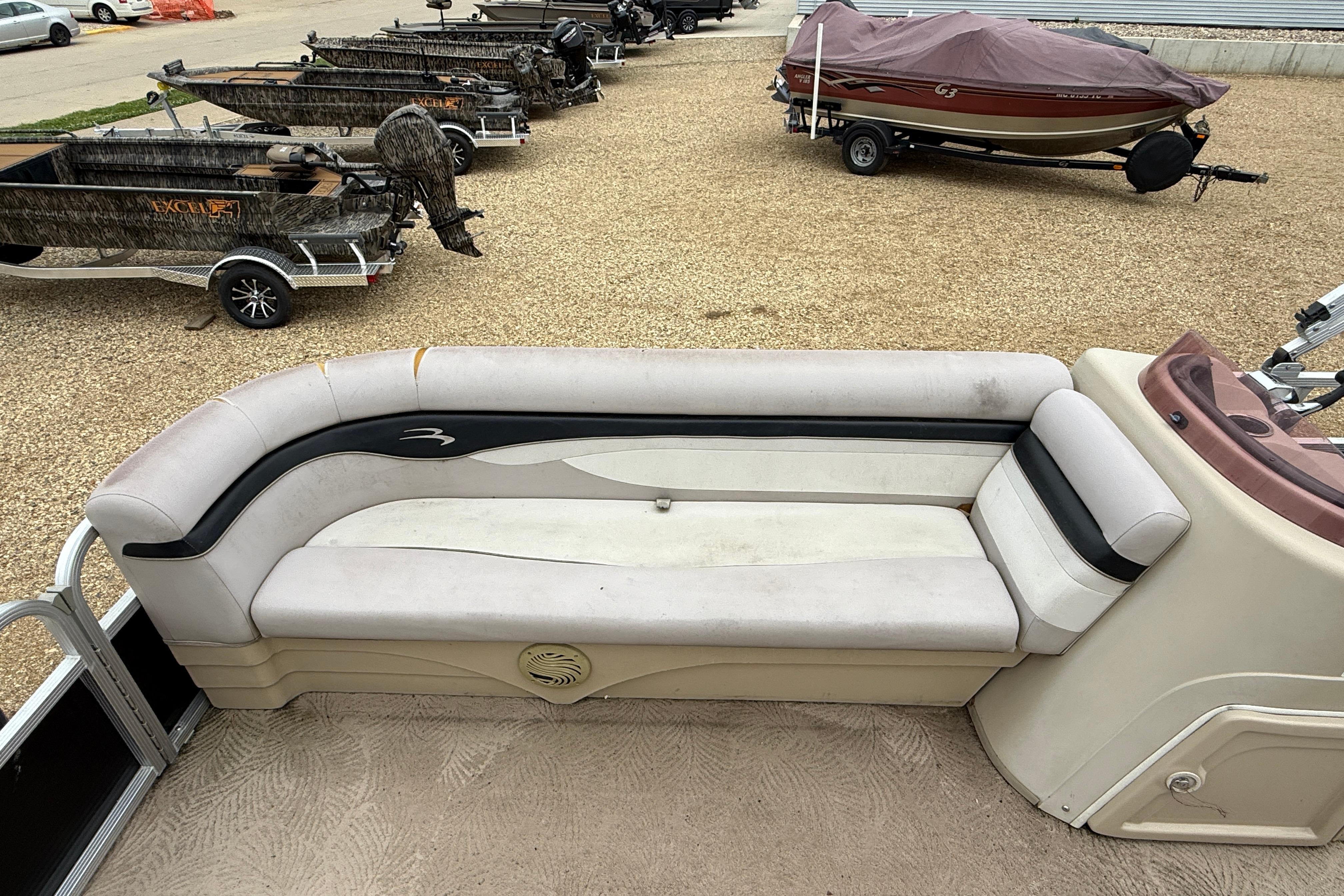 2010 Bennington 20SLi pontoon boat interior with beige seating, parked on gravel.