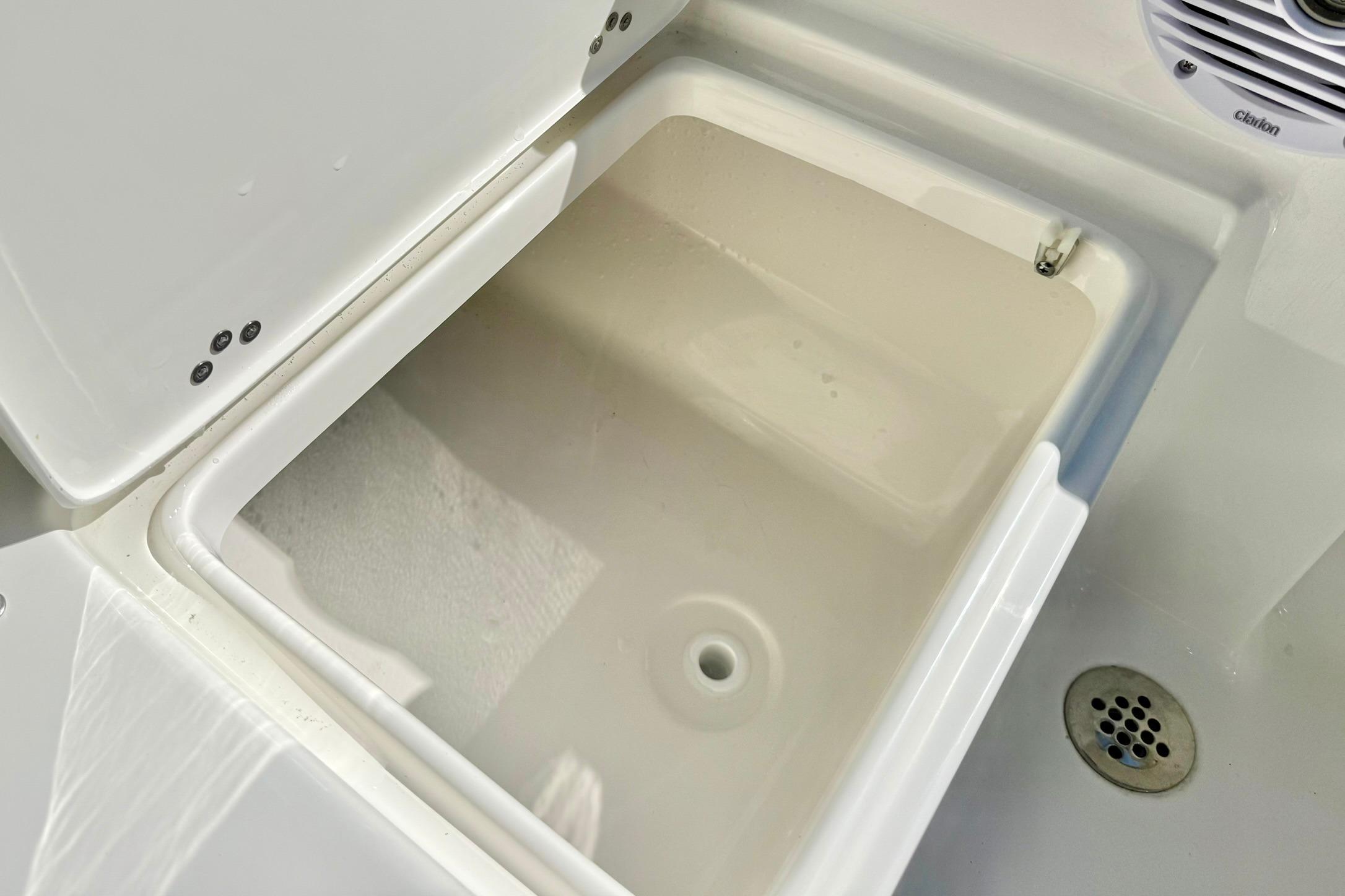 Open storage compartment on 2026 Key West 189 FS boat, featuring a drain and speaker.