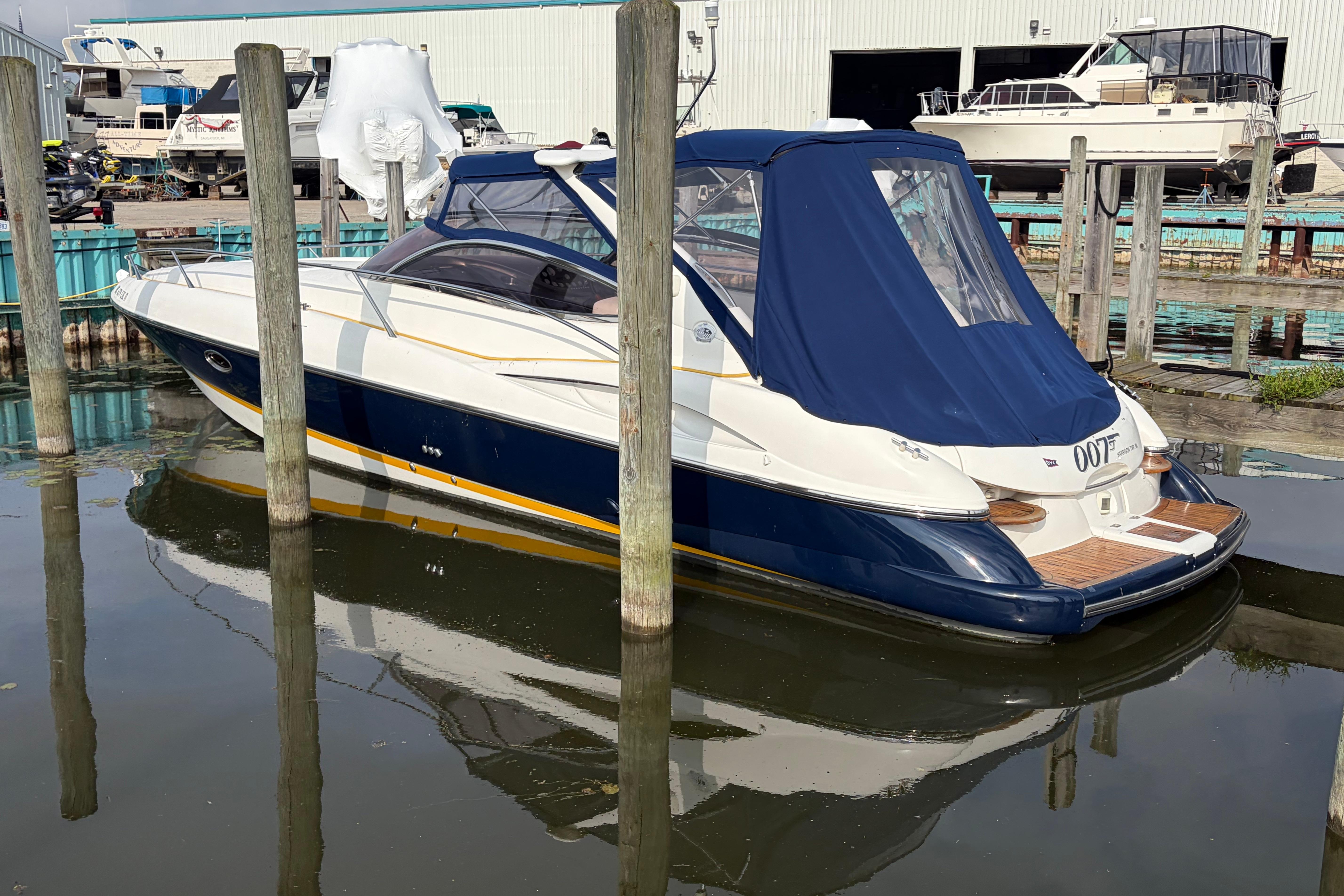 Sunseeker Superhawk 34, 2000 model, docked in a marina with blue cover.