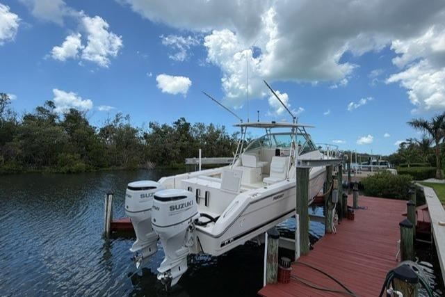 2004 Pursuit 3070 Express boat docked with twin Suzuki engines under a cloudy sky.