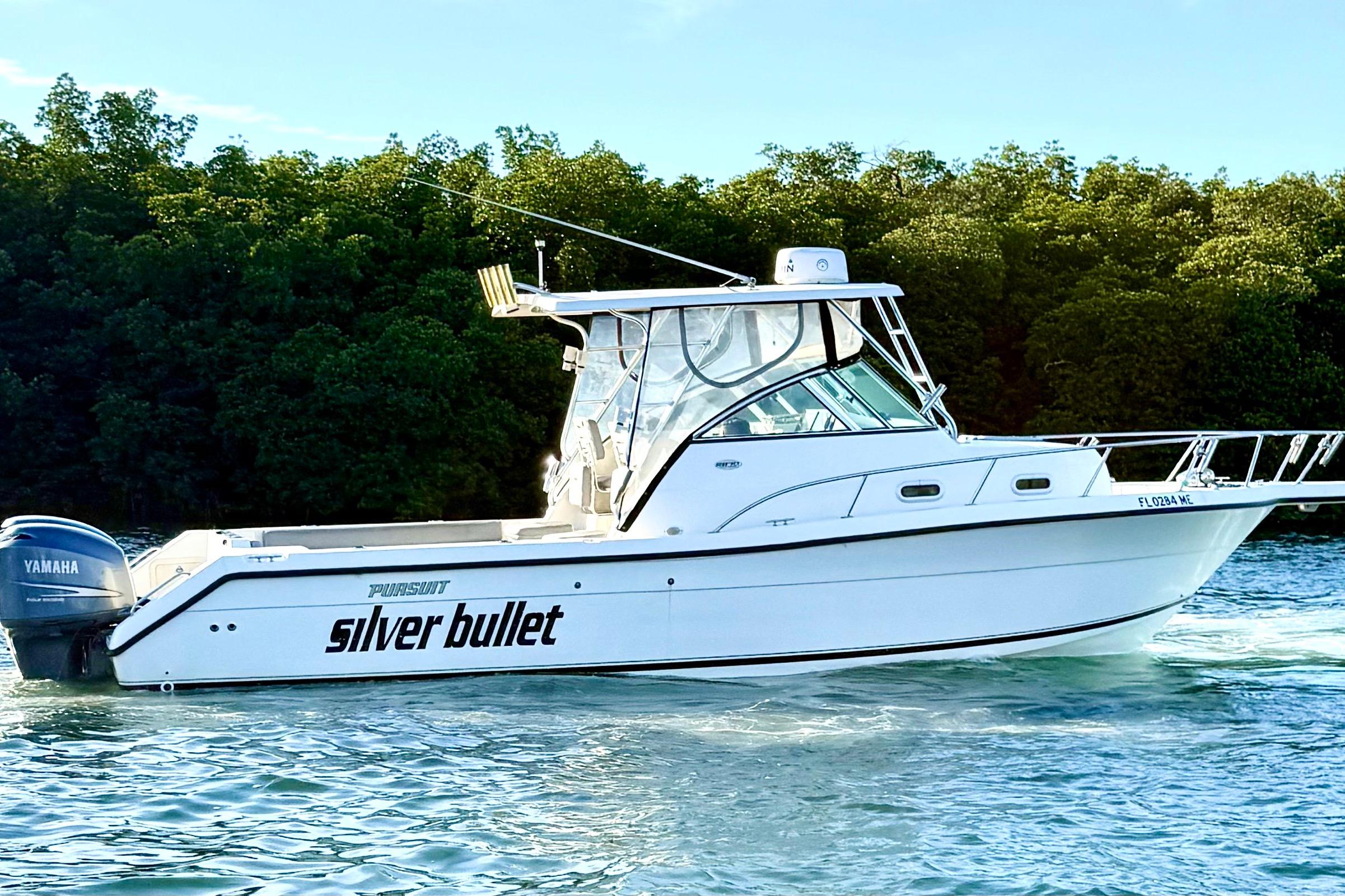 2003 Pursuit 2870 Walkaround boat named "Silver Bullet" on water near lush greenery.