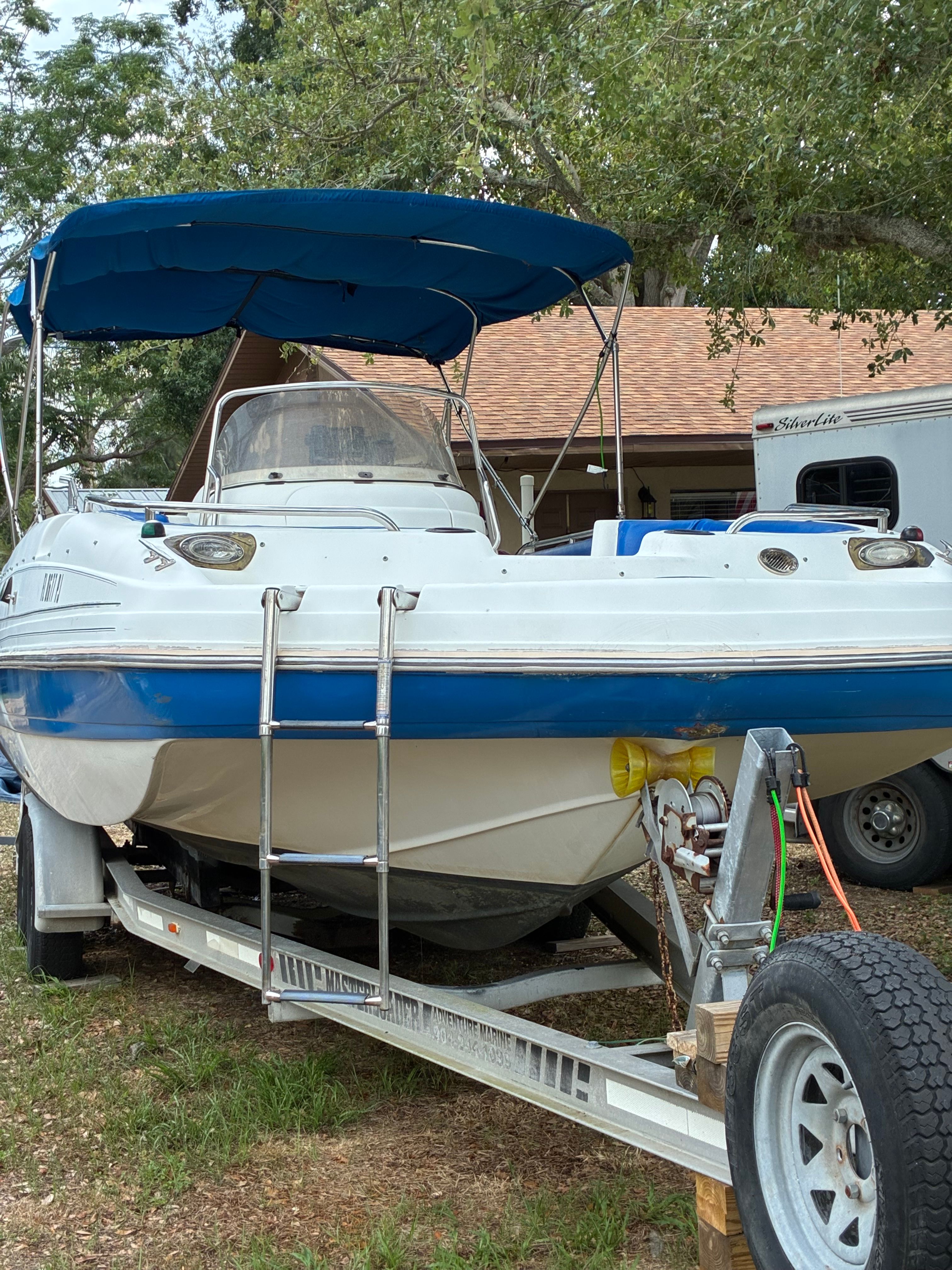 A 2012 Hurricane SunDeck Sport 231 OB on a trailer, featuring a blue sunshade.