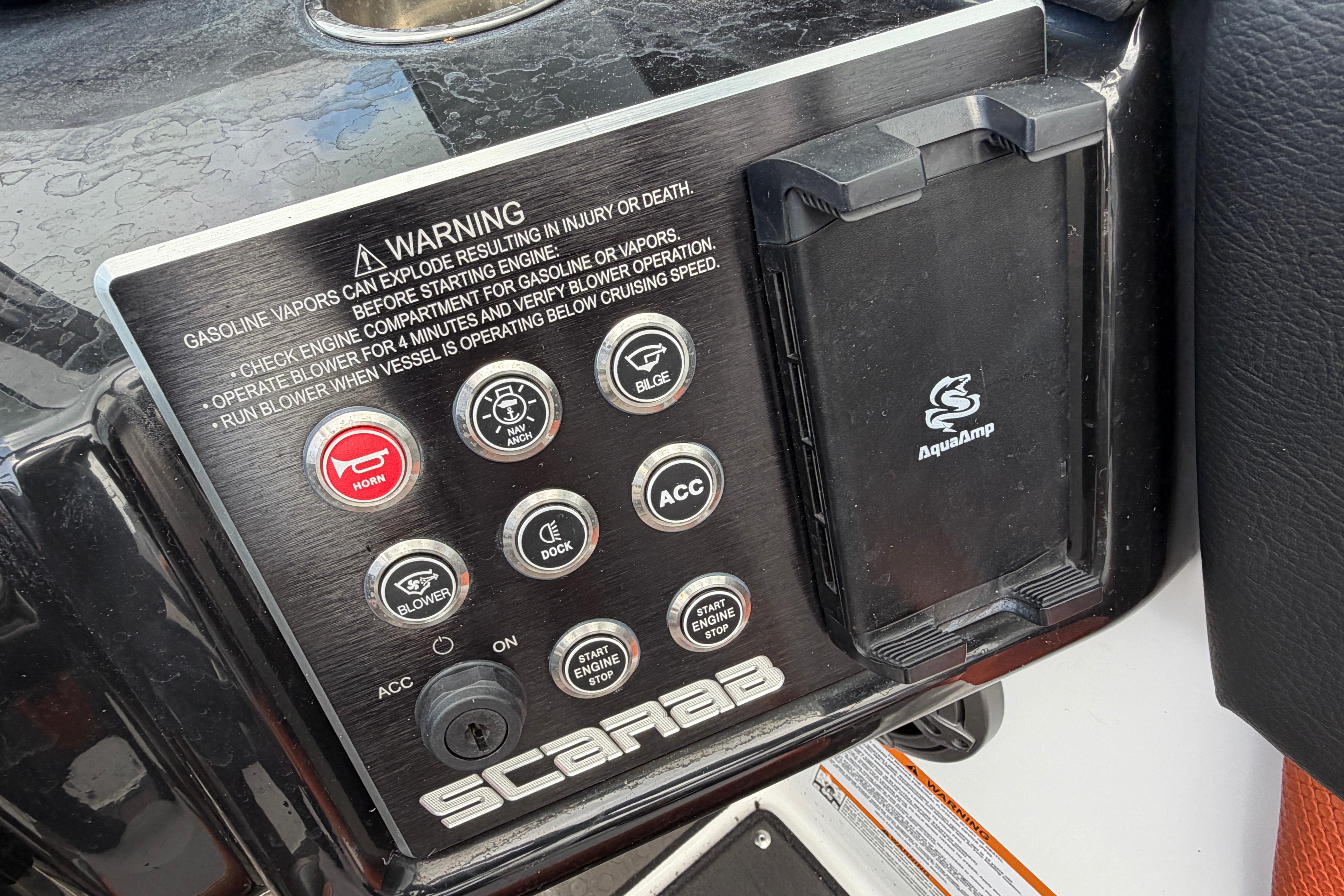 Control panel of 2026 Scarab 235 LX boat with warning labels and buttons.