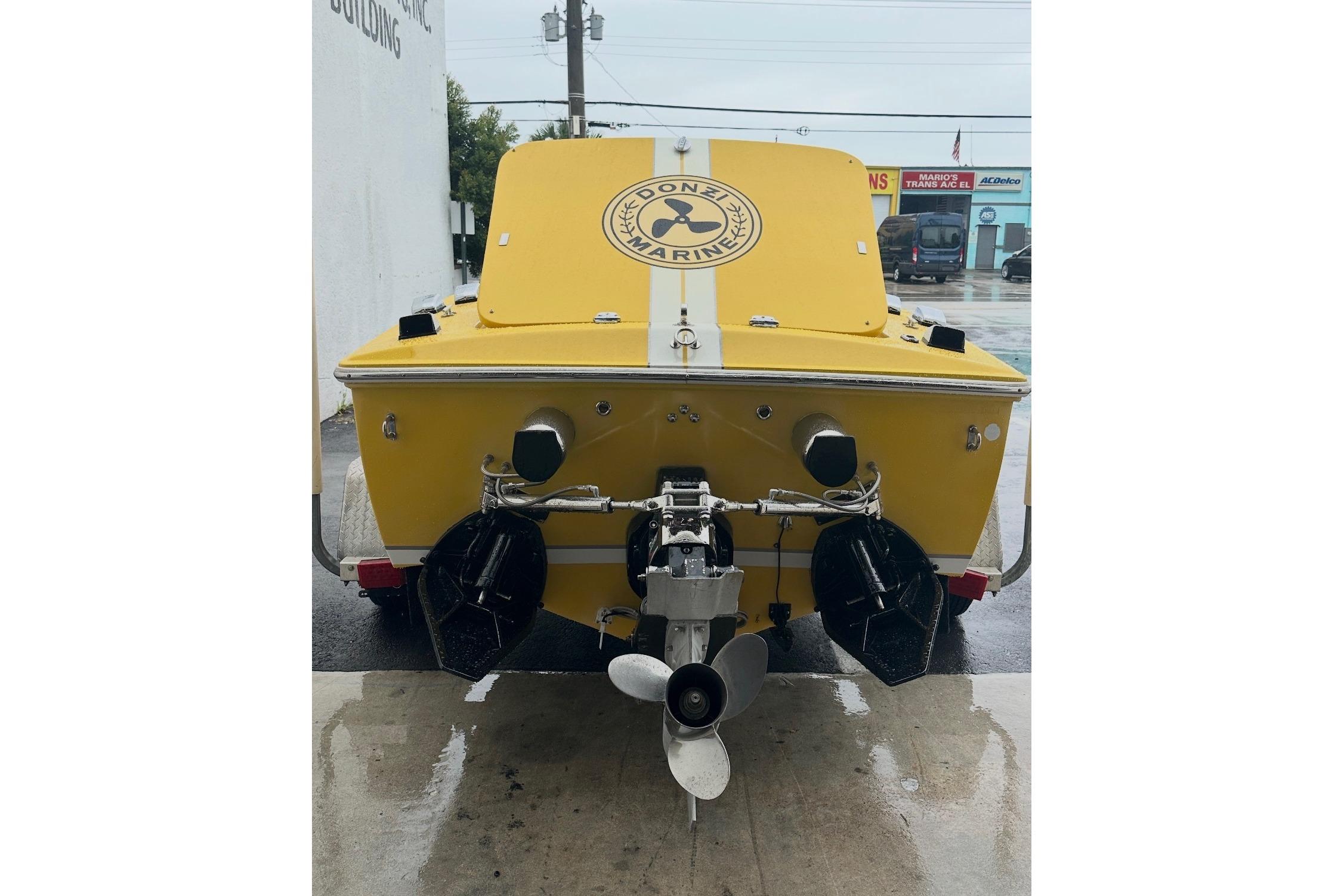 Yellow 2004 Donzi 22 Classic boat, rear view, showcasing dual propellers and sleek design.