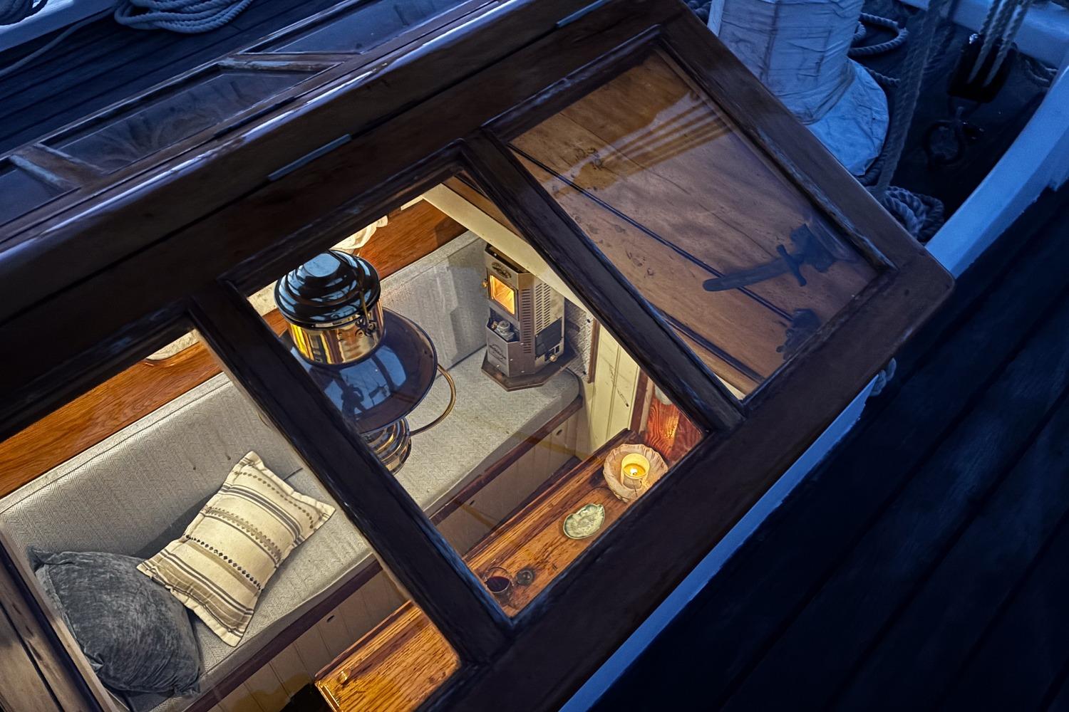 Cozy interior of 2004 Custom Luke Powell Pilot Cutter with cushions and lantern.