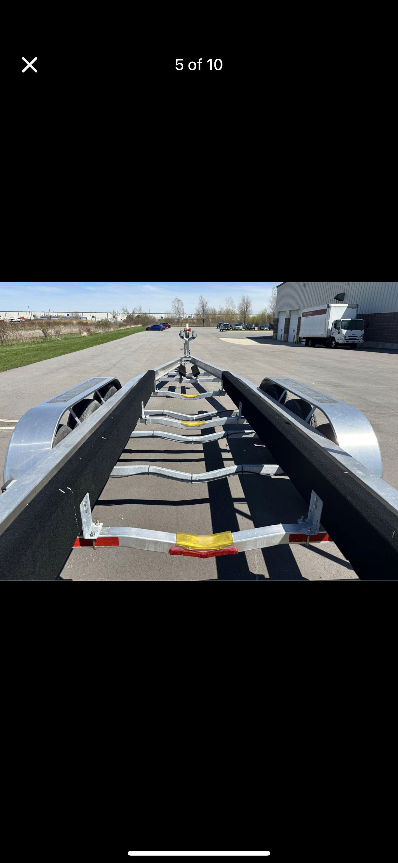 A boat trailer is parked on a lot, ready for transporting a boat.