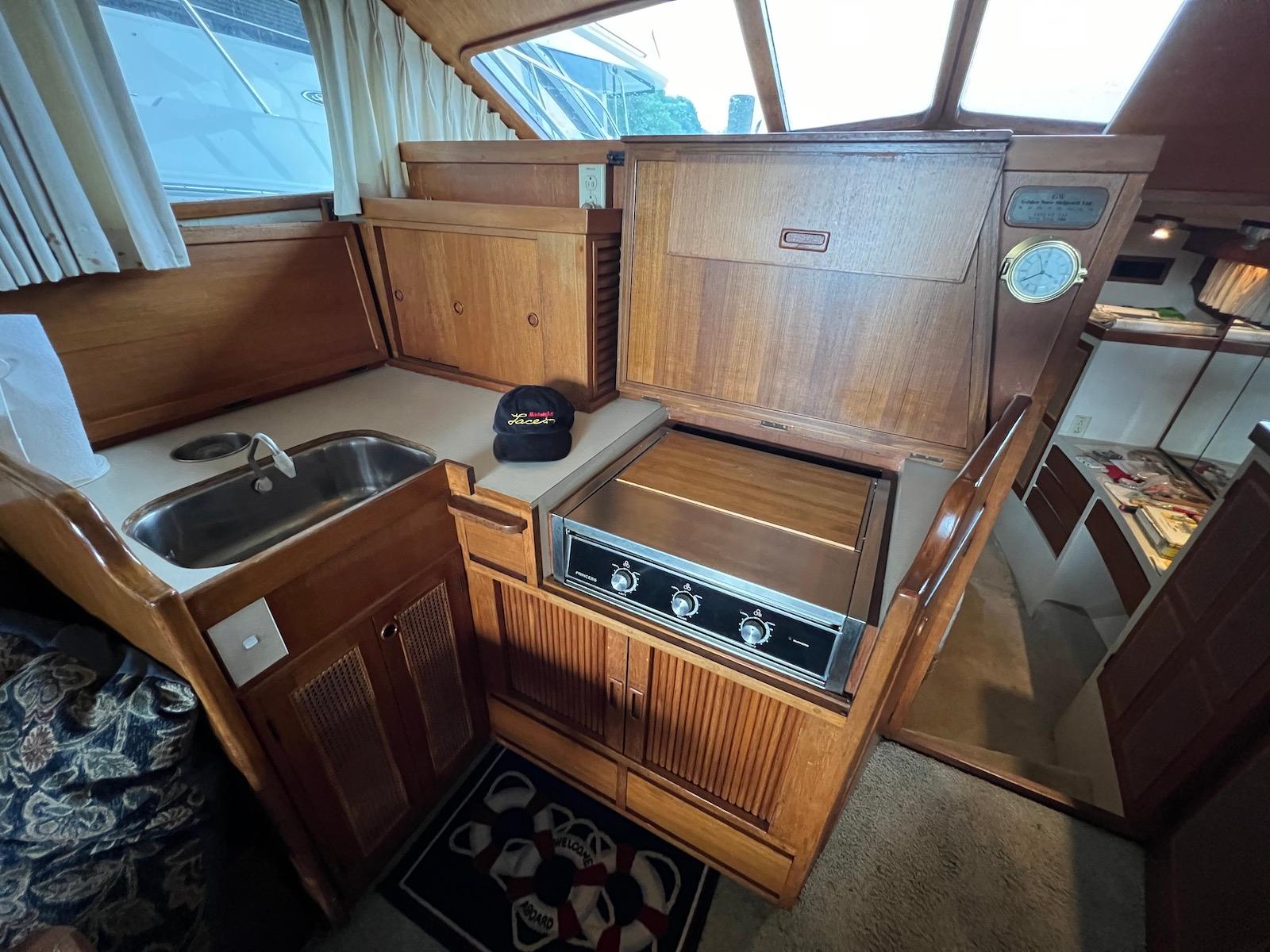 1986 Midnight Lace 44 Flybridge Express Cruiser kitchen with wood cabinetry and compact appliances.