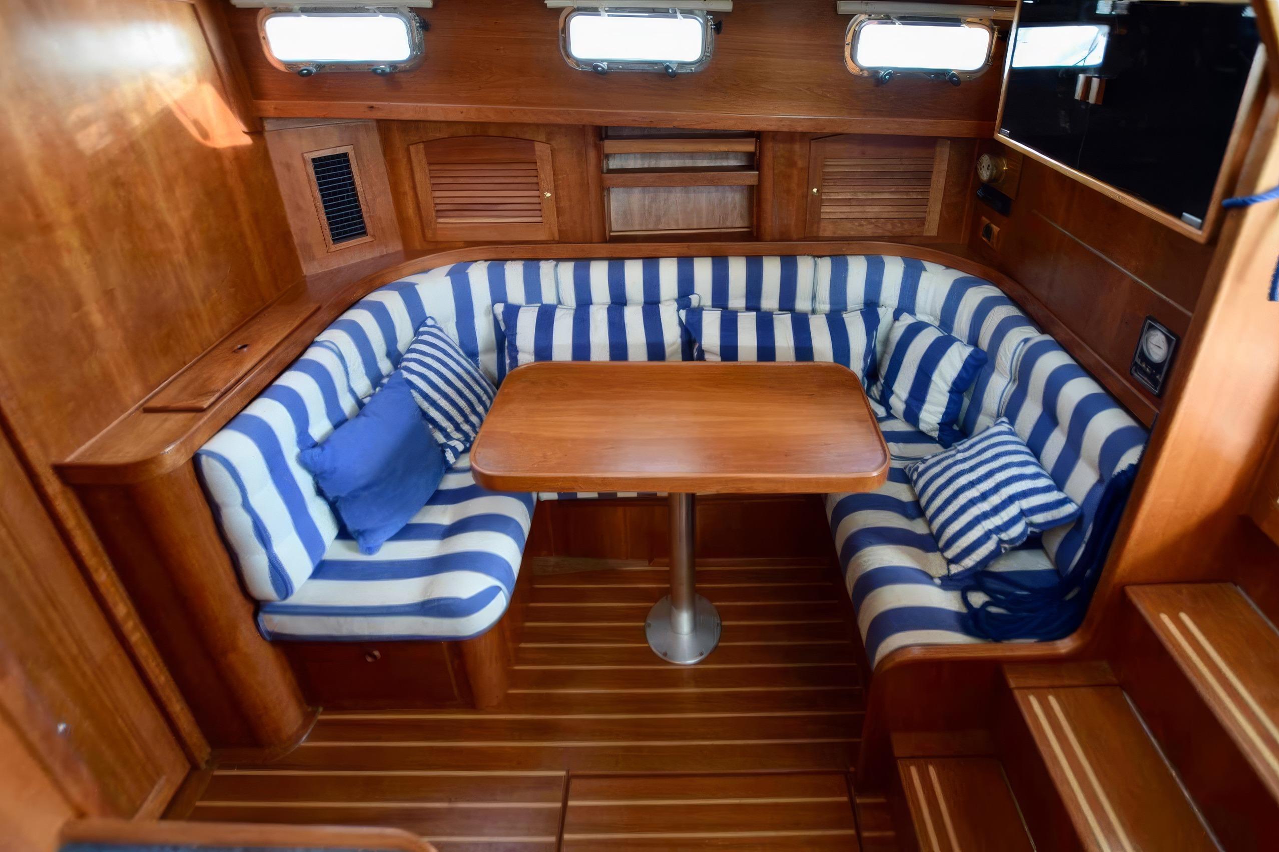 Cozy interior of 2001 Sabreline 36 Express with striped seating and wooden table.