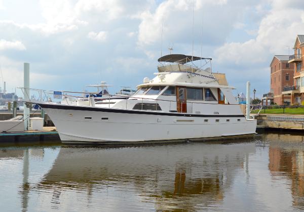 A white 1980 Hatteras 53 Yacht Fisherman is docked in a calm harbor.