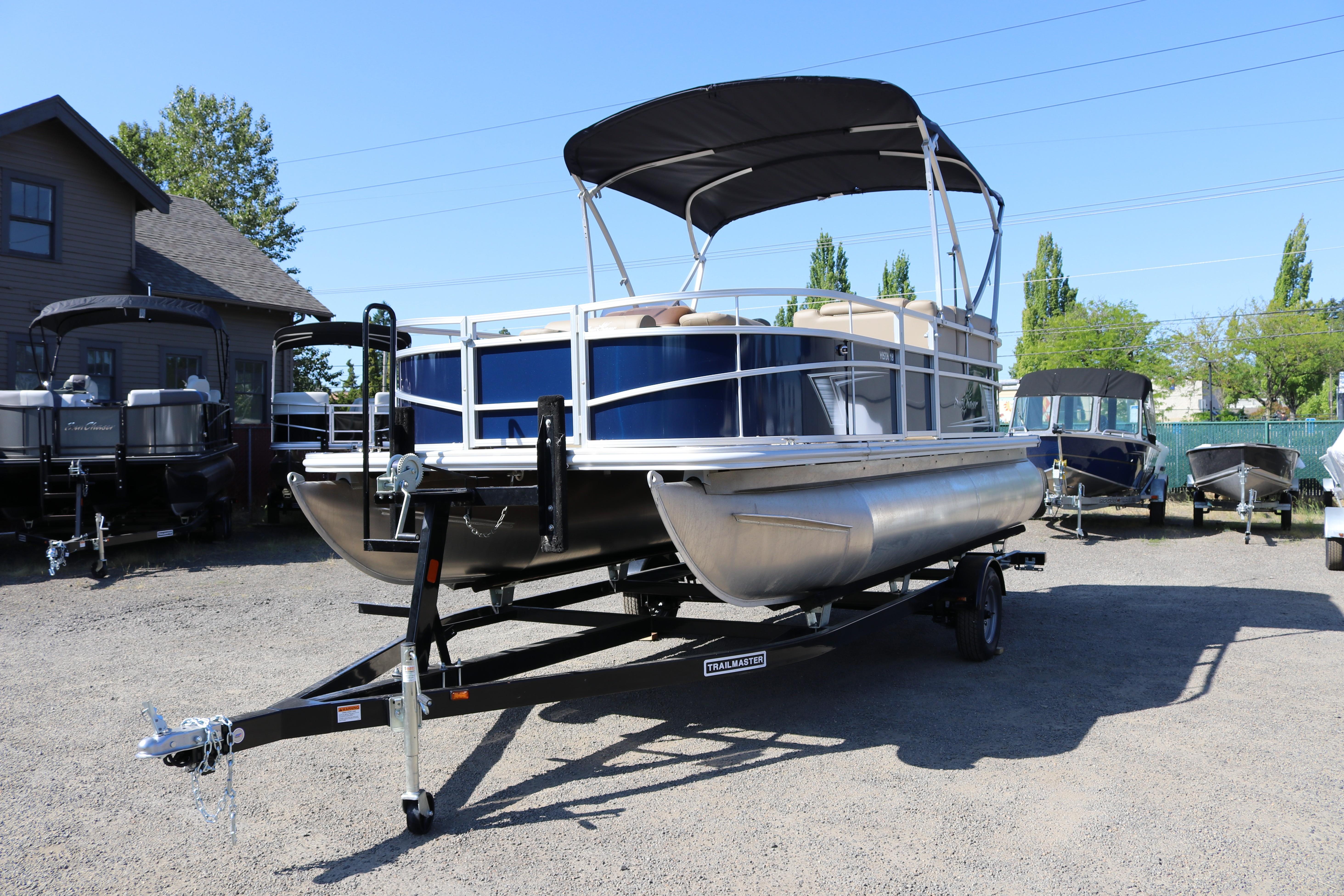 2025 Sun Chaser Vista Fish 18 pontoon boat on trailer in outdoor lot.