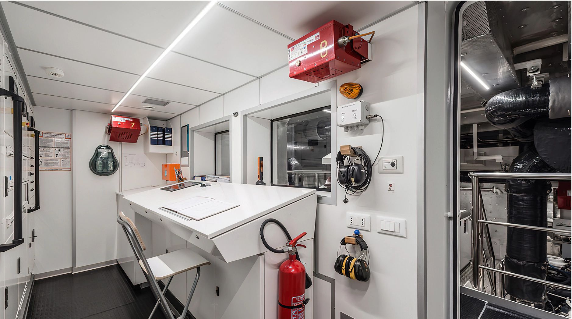 Interior of a modern boat with a desk, fire extinguisher, and technical equipment.