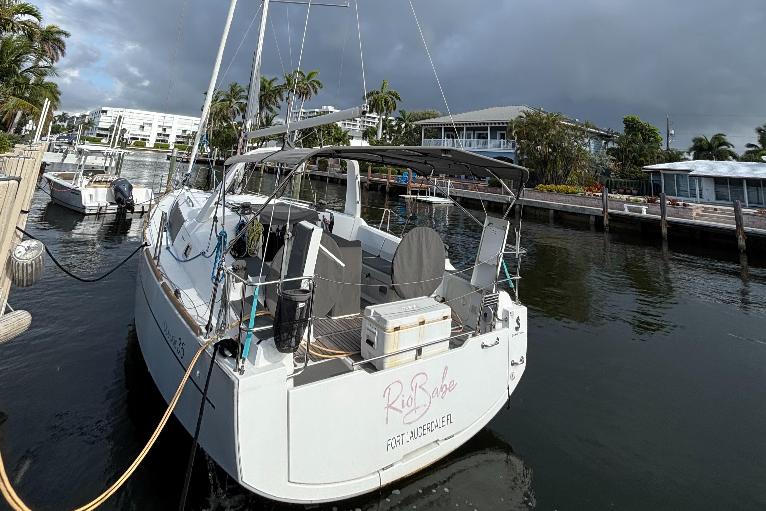 2015 Beneteau Oceanis 35 docked in a marina, surrounded by palm trees.