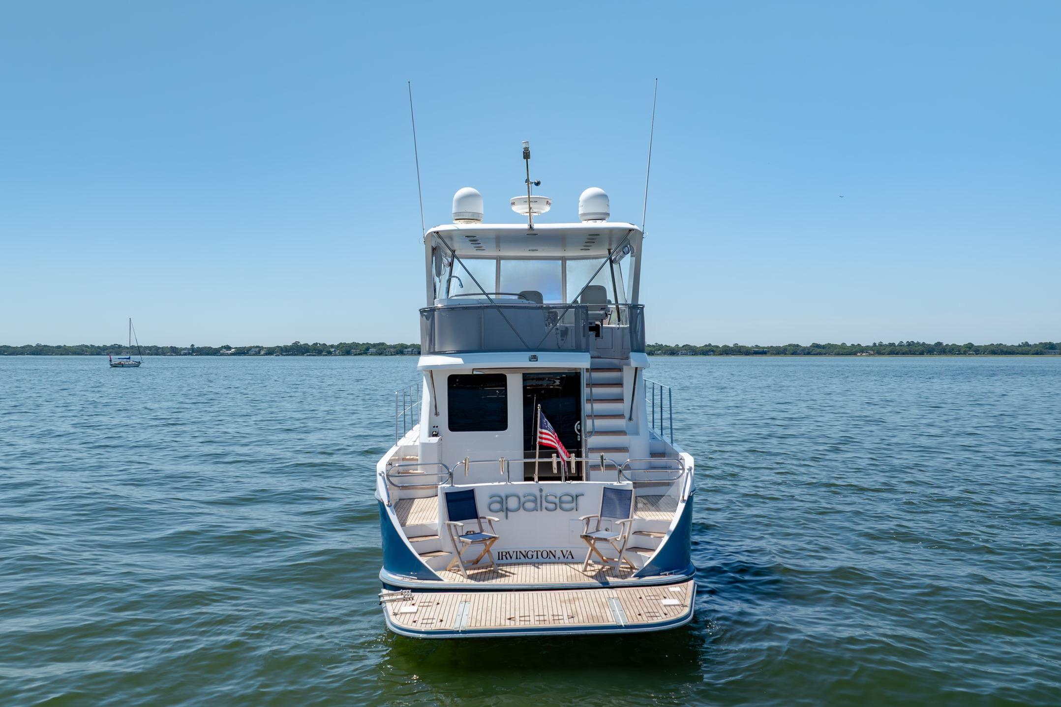 Ocean Alexander yacht on calm waters, rear view with clear sky background.