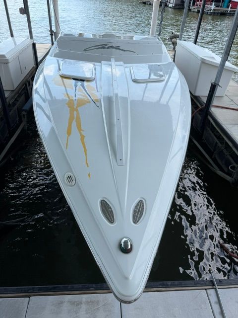 A white speedboat docked in a marina, featuring yellow accents on the deck.