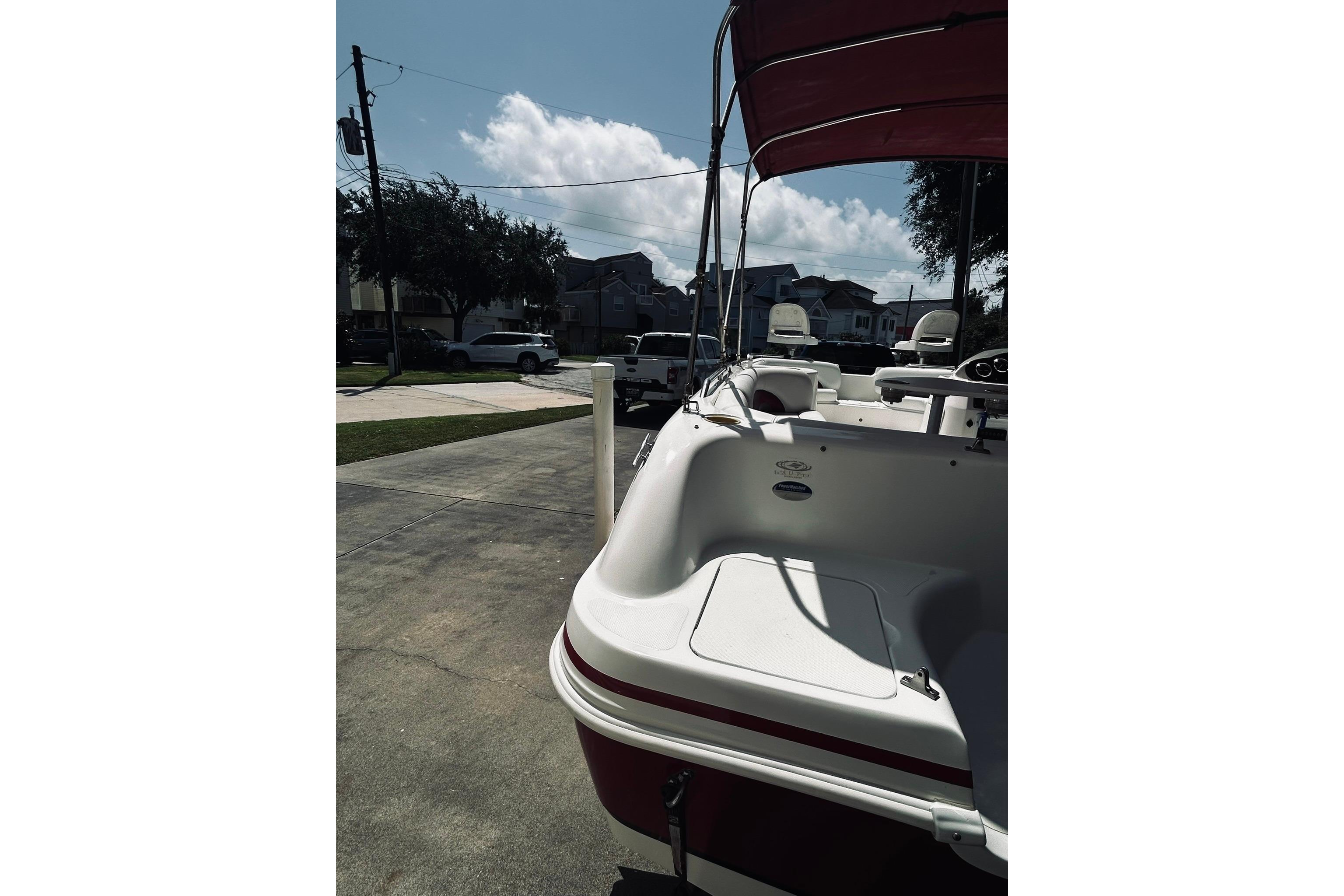 2013 Hurricane SunDeck Sport 201 OB boat parked in a residential driveway under a clear sky.