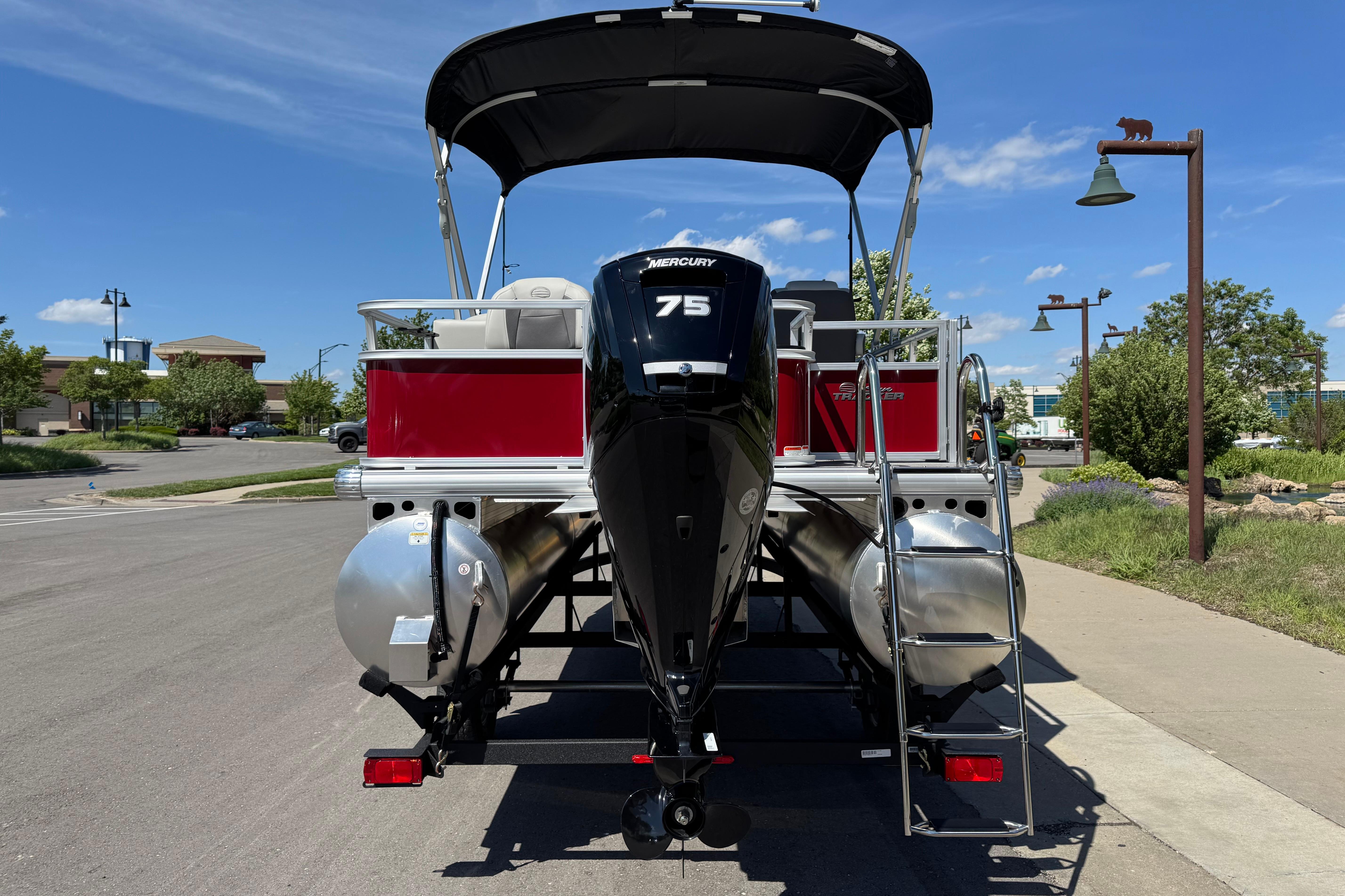 2026 Sun Tracker Bass Buggy 18 DLX pontoon boat with Mercury 75 engine, parked outdoors.