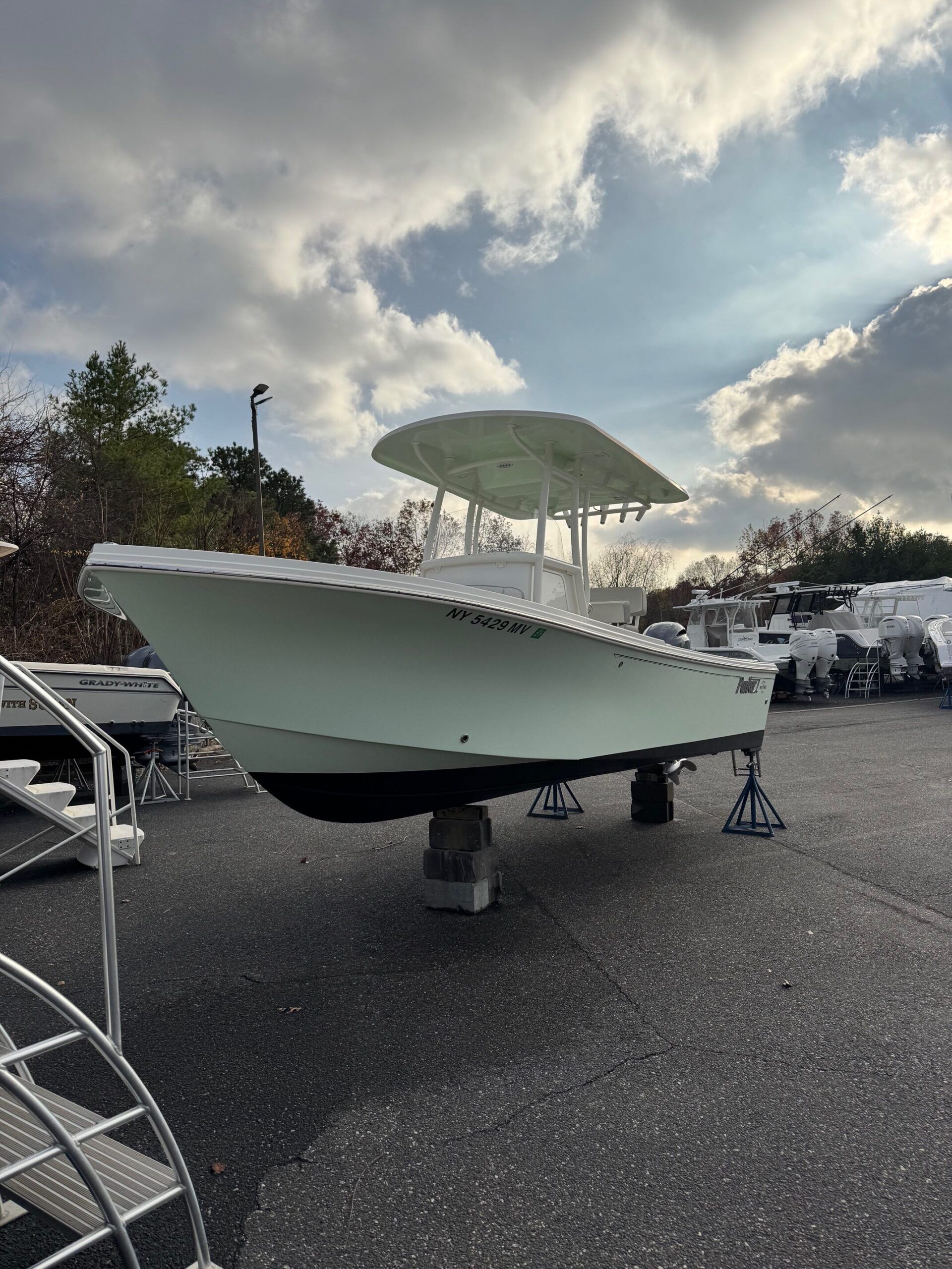Sportsman Open 232 Center Console 2023 on a lot, surrounded by trees and clouds.
