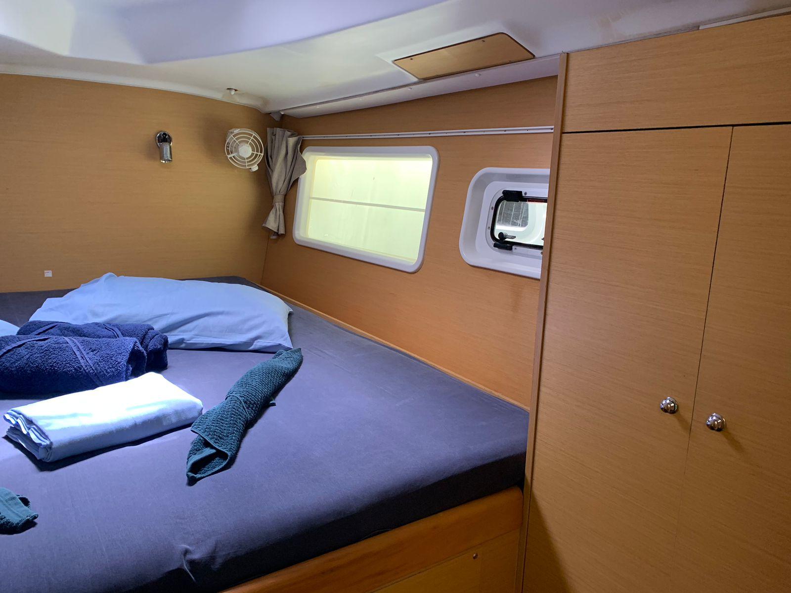 Interior cabin of 2016 Lagoon 380 catamaran with bed, window, and wooden cabinetry.