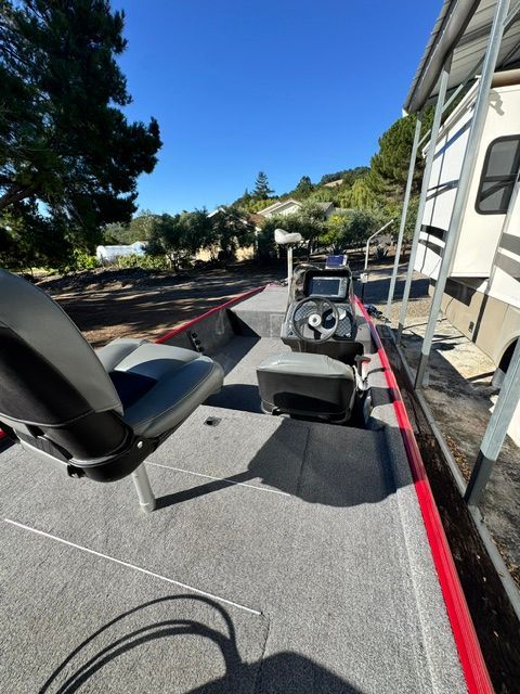 A Bass Tracker boat with gray carpet flooring and a helm. It is on dry land.