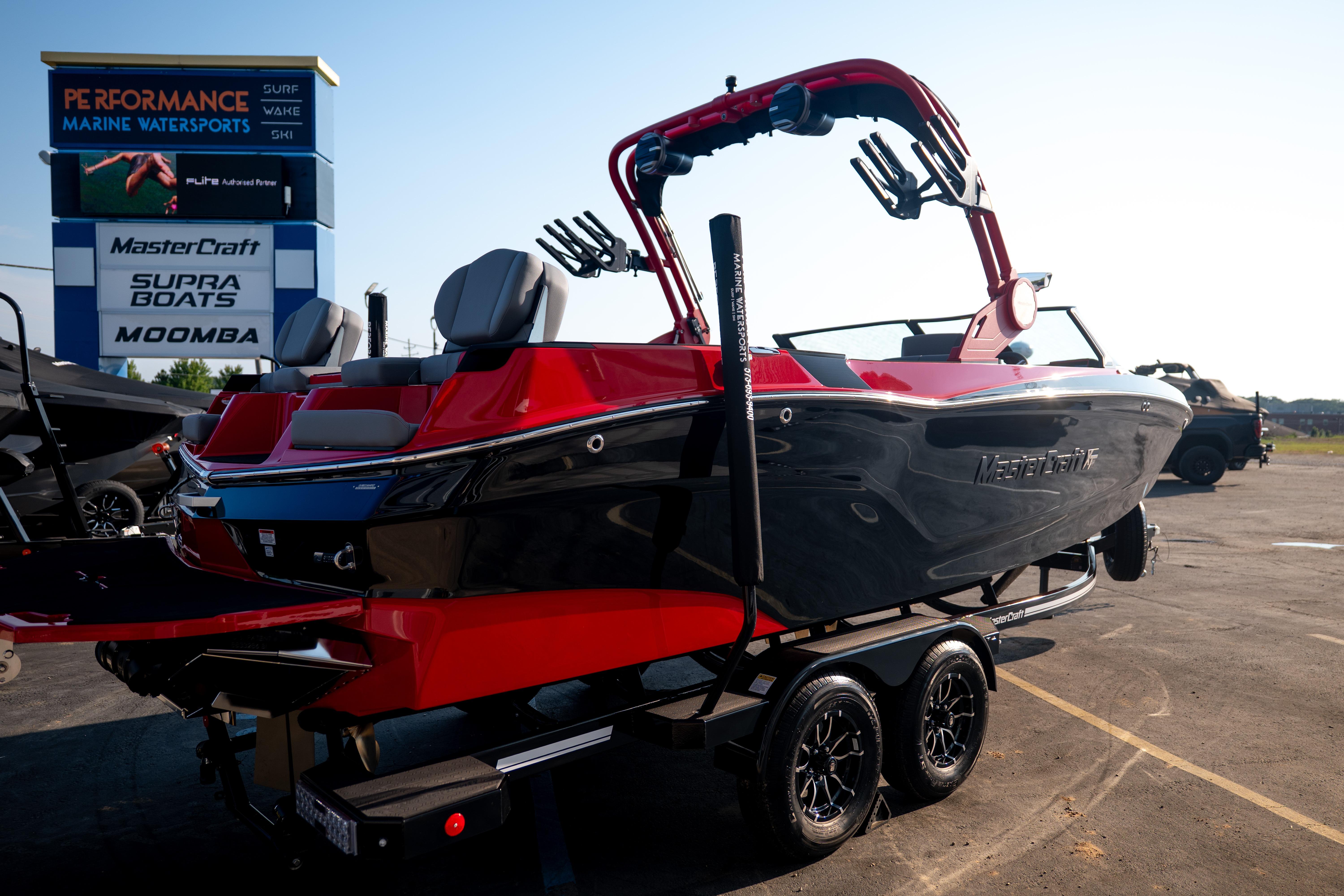 2027 MasterCraft XT24 boat in red and black on trailer at marine dealership.