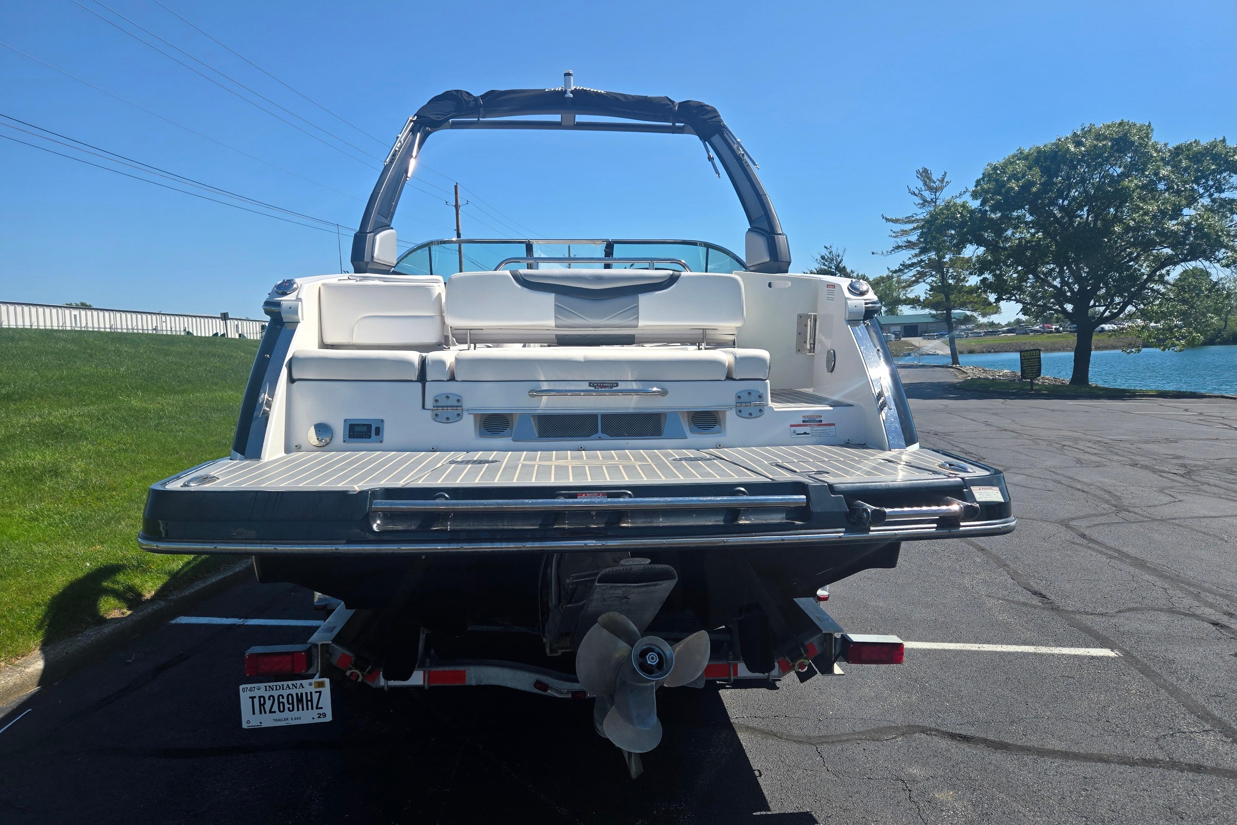 2018 Chaparral 267 SSX boat rear view, parked near a lake on a sunny day.