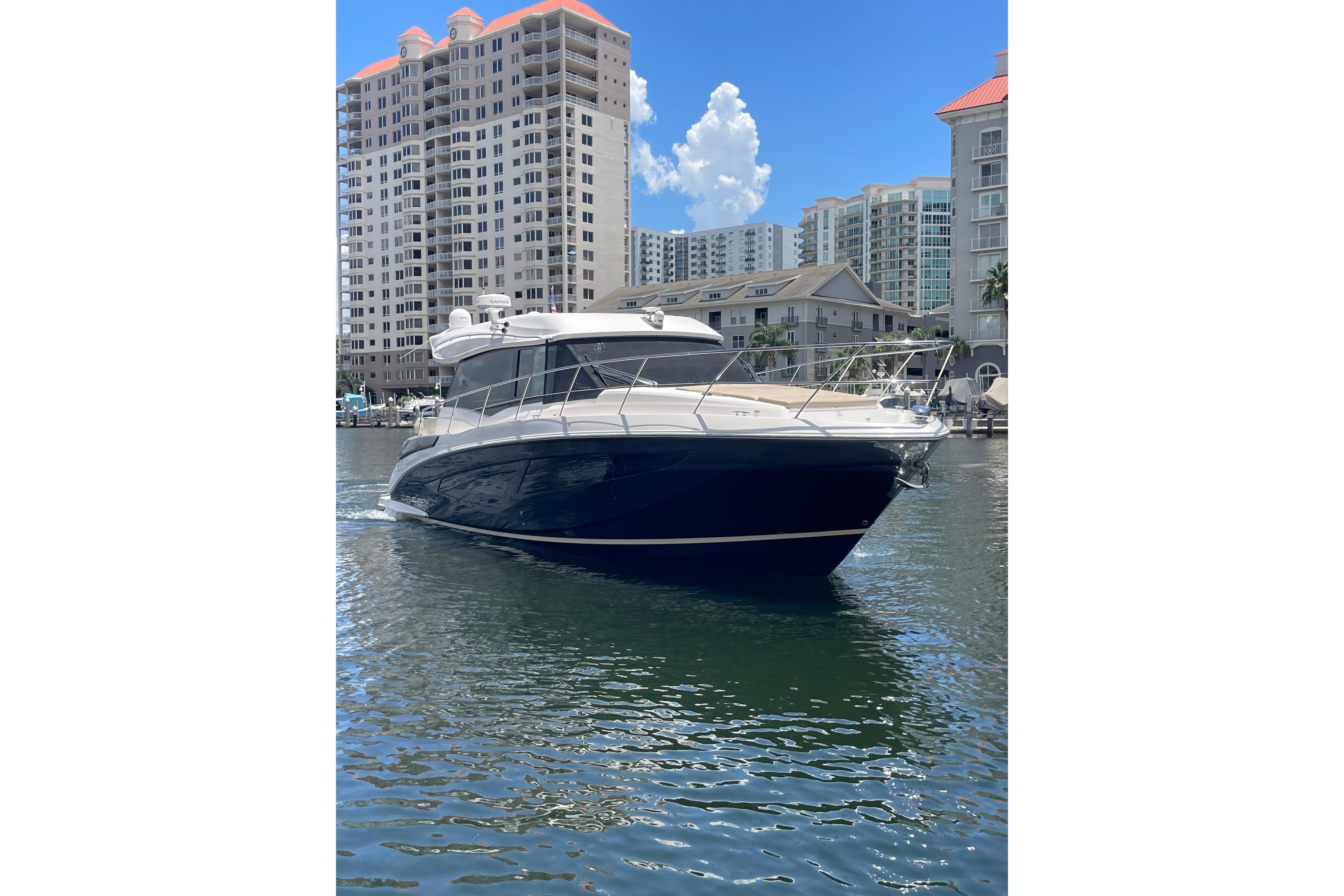 A Regal 42 Grande Coupe boat on the water in front of high-rise buildings.