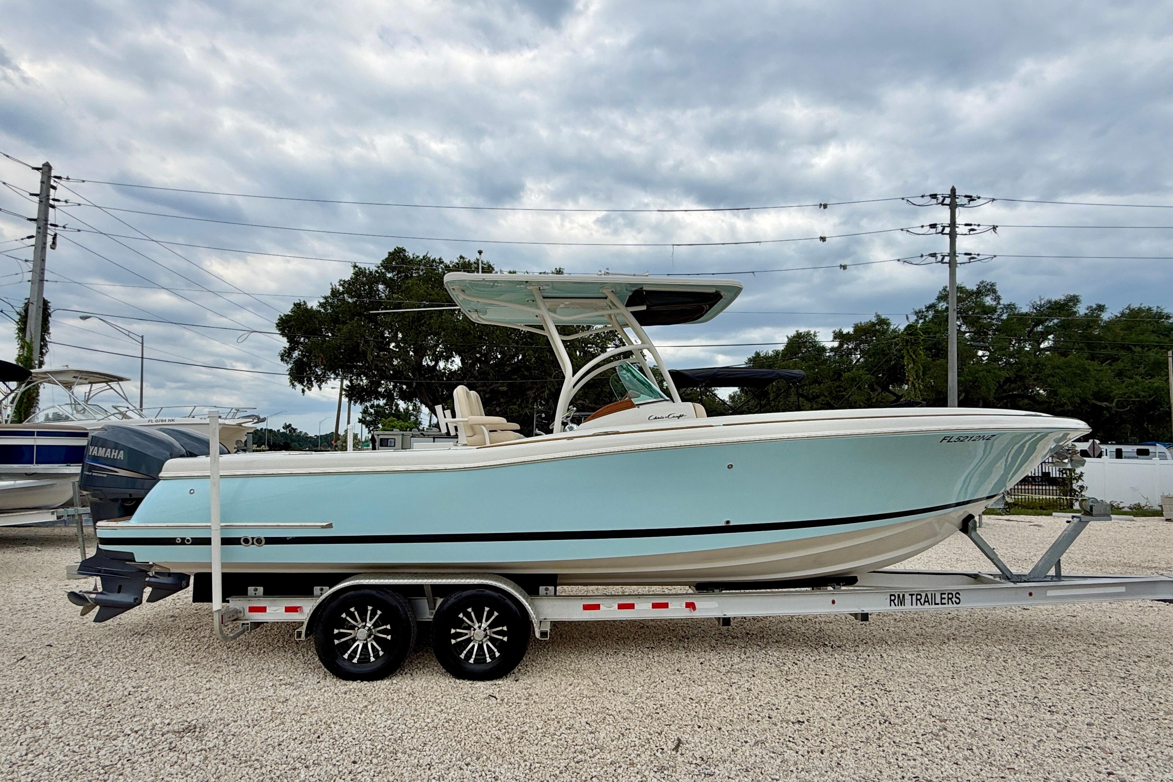2010 Chris-Craft Catalina 29 boat on trailer, light blue hull, parked outdoors.