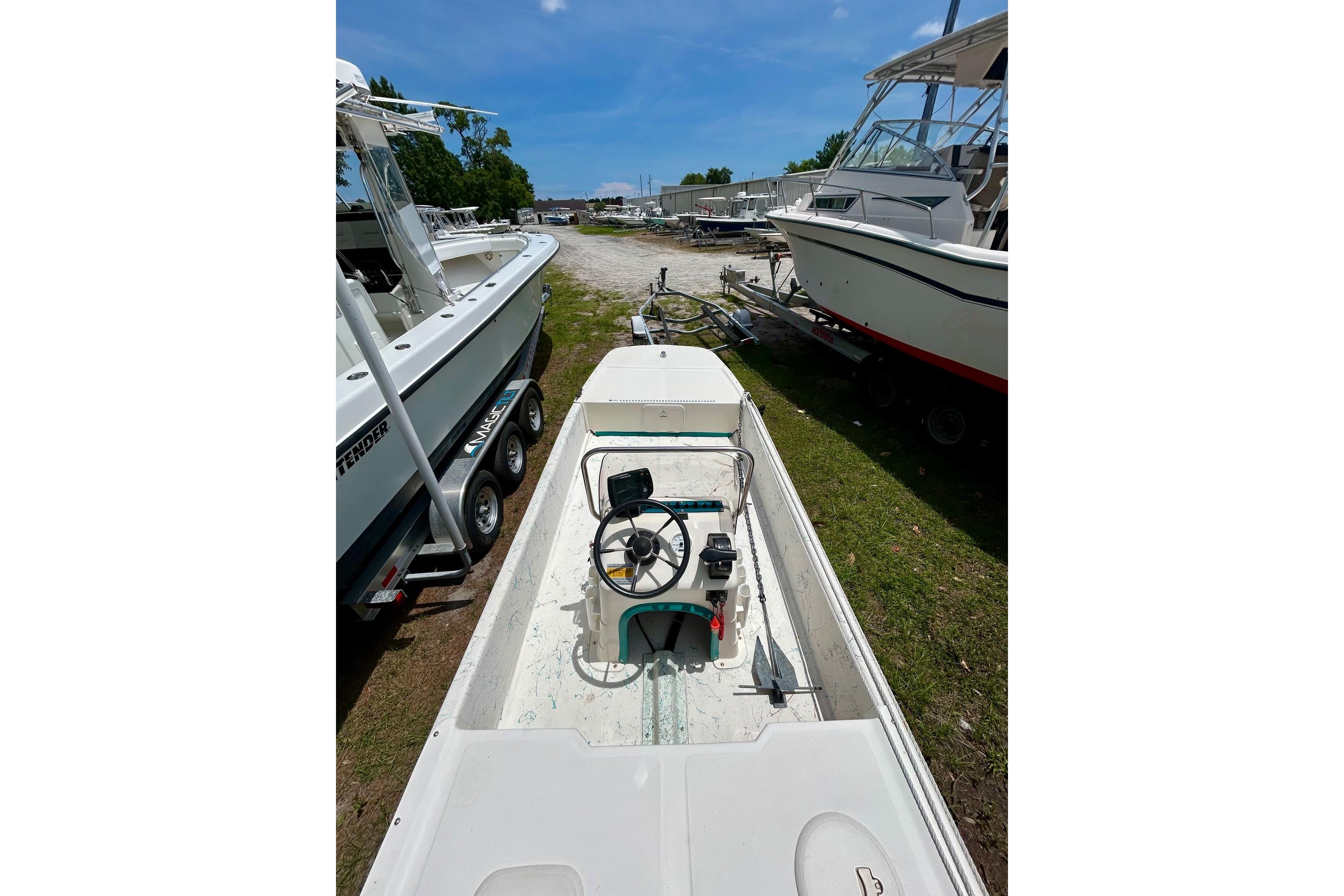 2002 Sundance K16CC boat parked outdoors, surrounded by other boats under a clear blue sky.