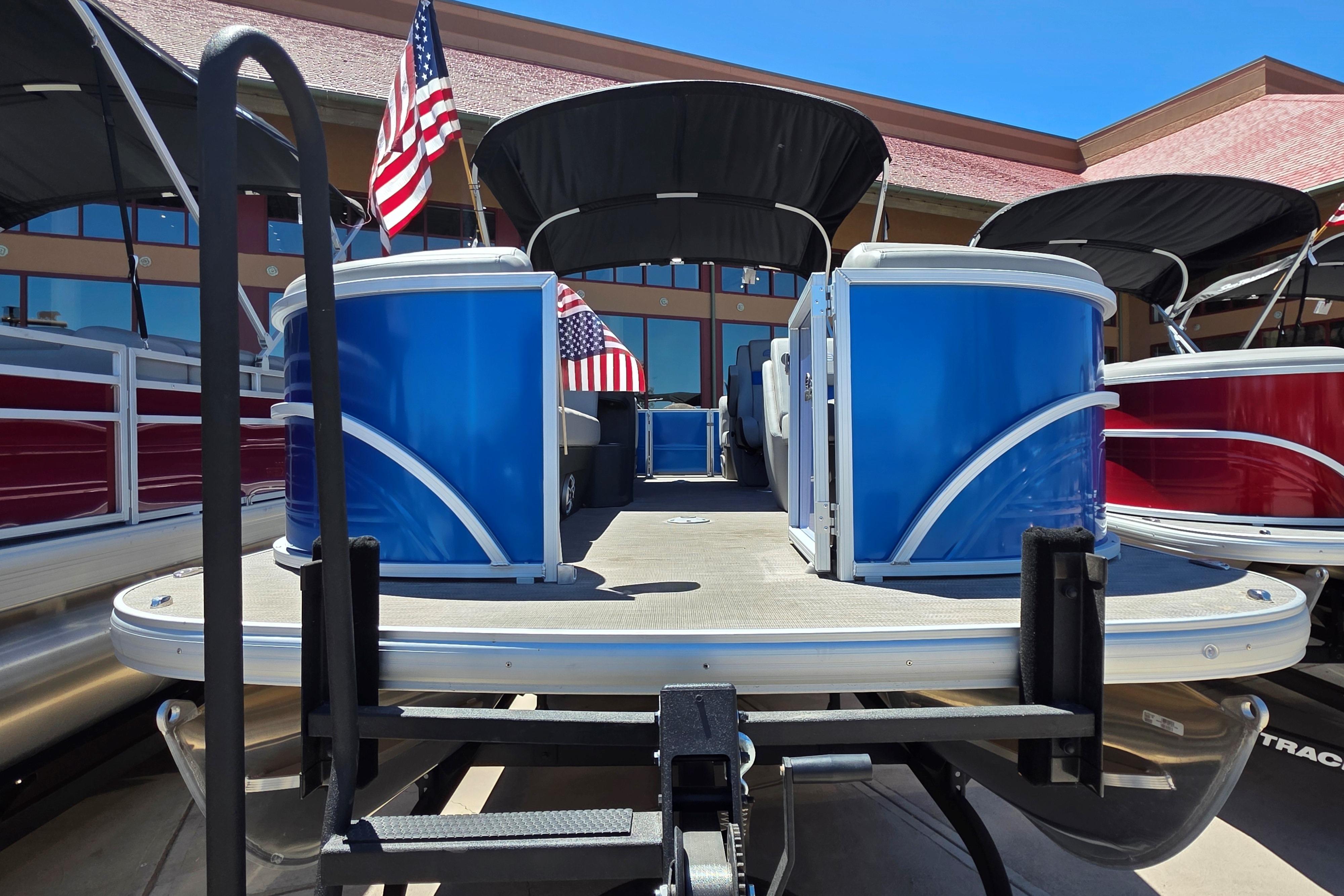 2026 Sun Tracker Party Barge 22 DLX pontoon boat with American flags displayed.