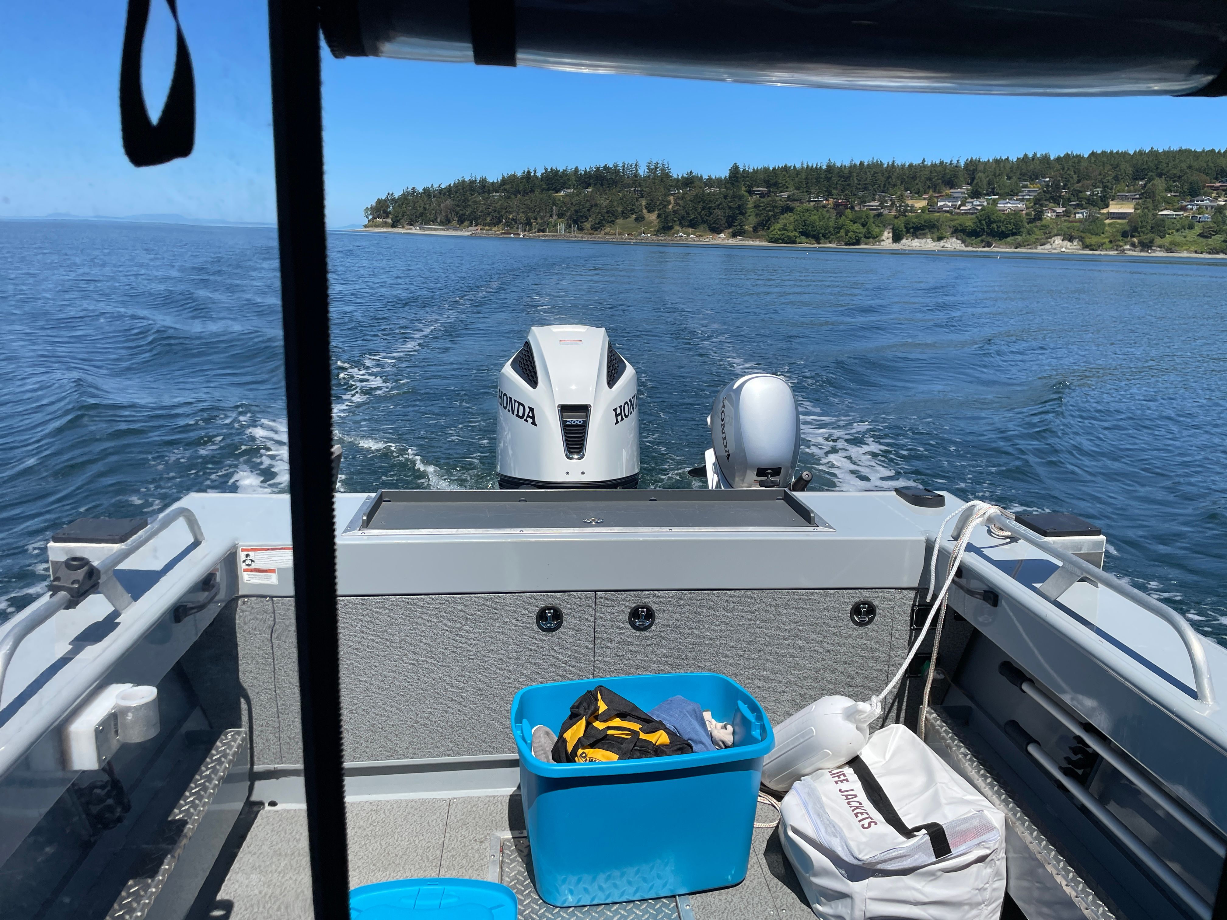 View from inside a boat looking out at the water, with a Honda motor and coastline in the background.