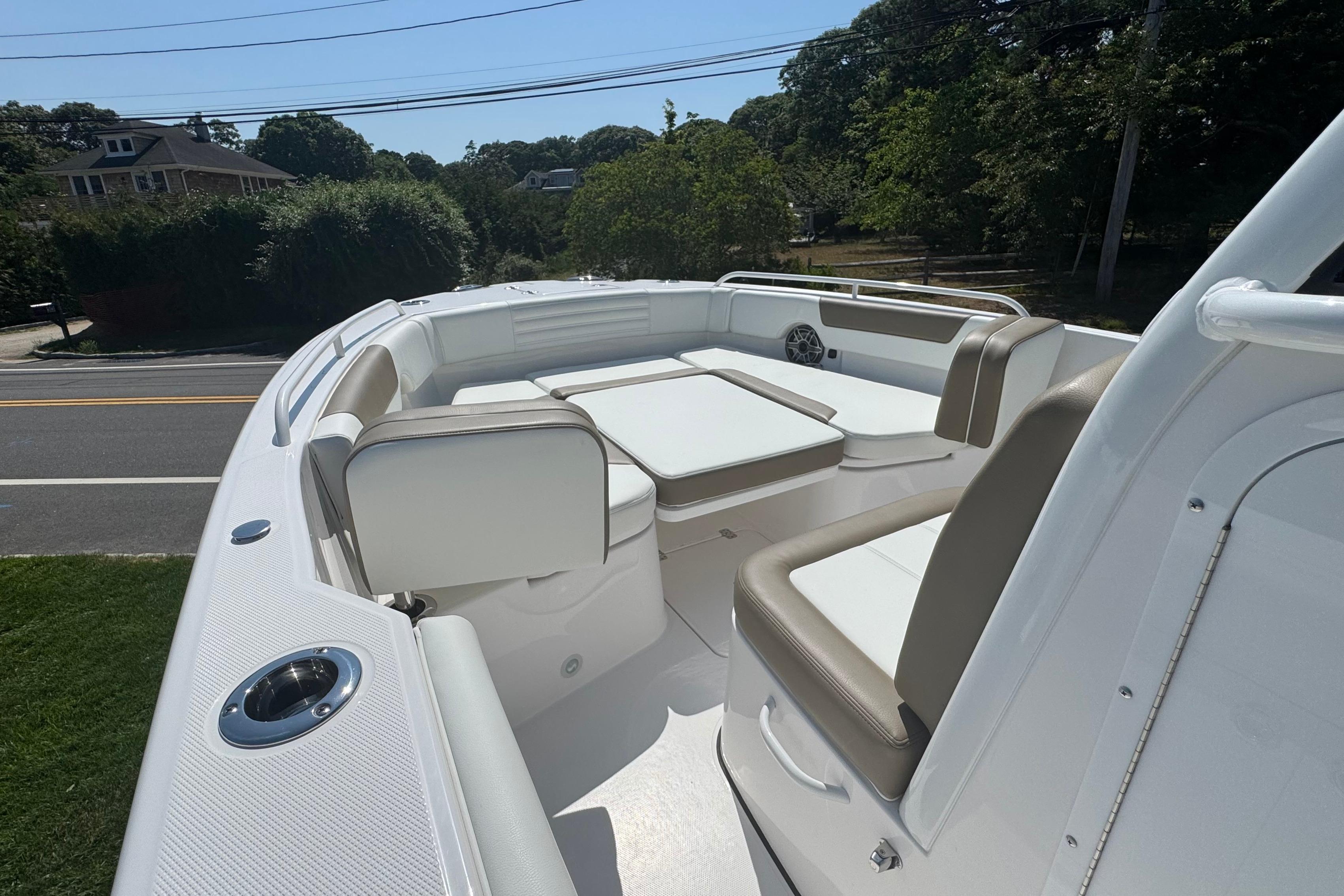 2026 Edgewater 250CC boat interior with cushioned seating and table, parked near a road.