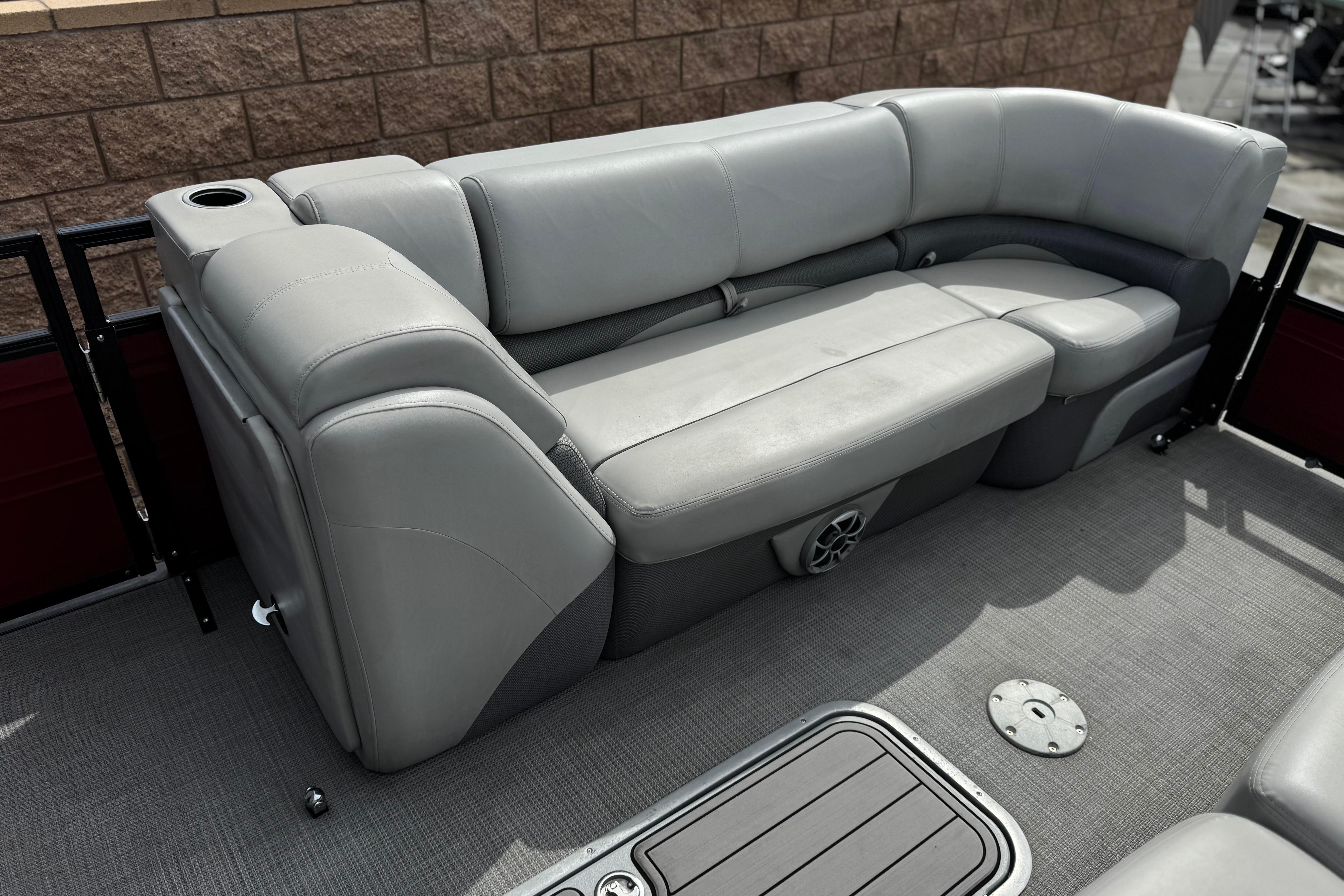 Luxurious seating on 2022 Regency 250 DL3 pontoon boat with gray upholstery and cup holder.