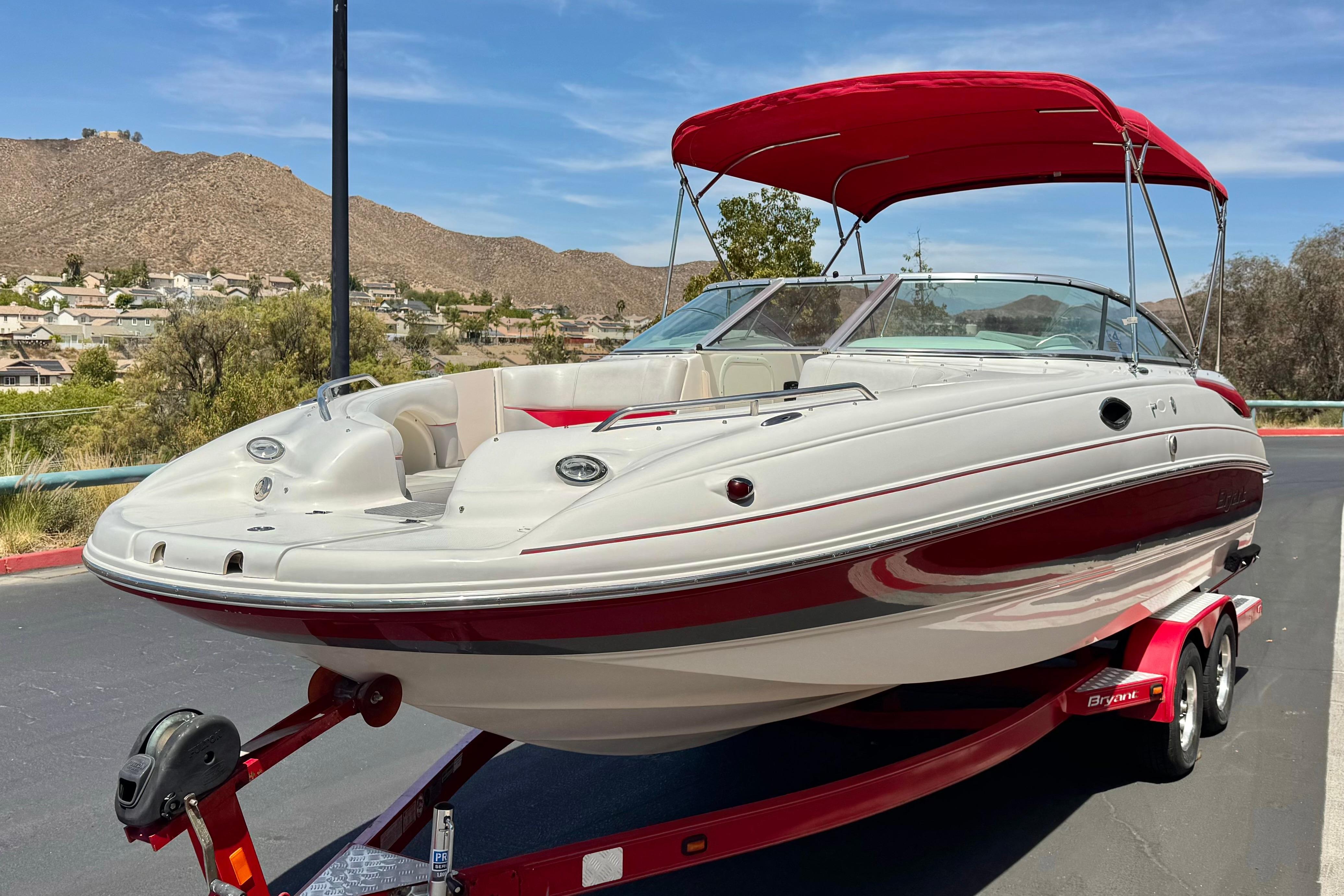 2010 Bryant 255 boat with red canopy on trailer, scenic background.