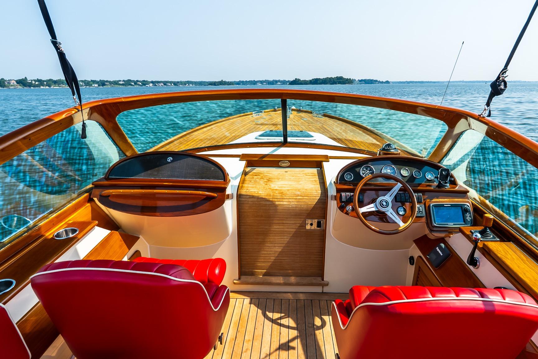 2005 Hinckley Talaria 29R boat interior with red seats and wooden dashboard on open water.