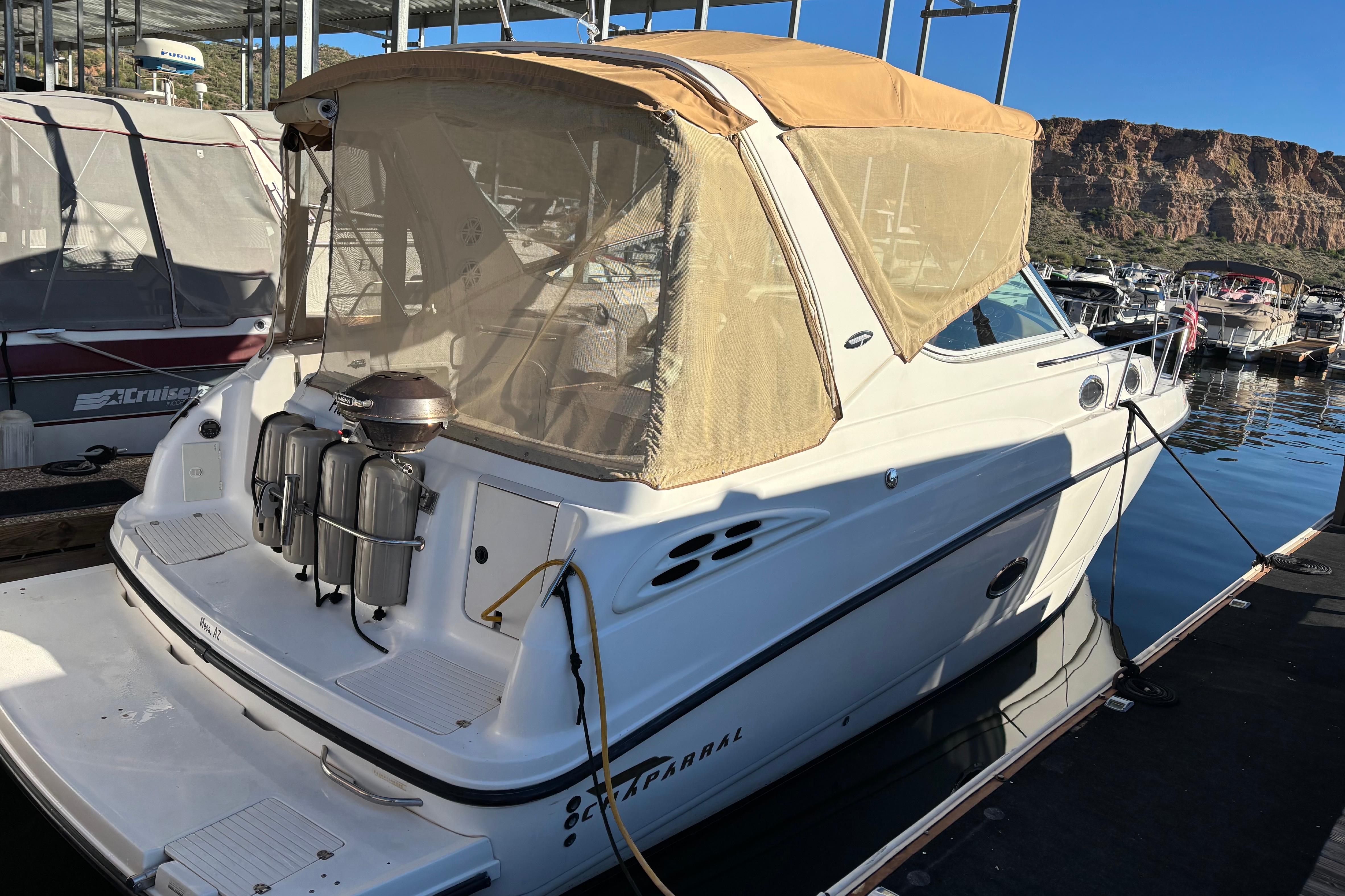 1999 Chaparral Signature 300 boat docked with tan canopy and scenic background.