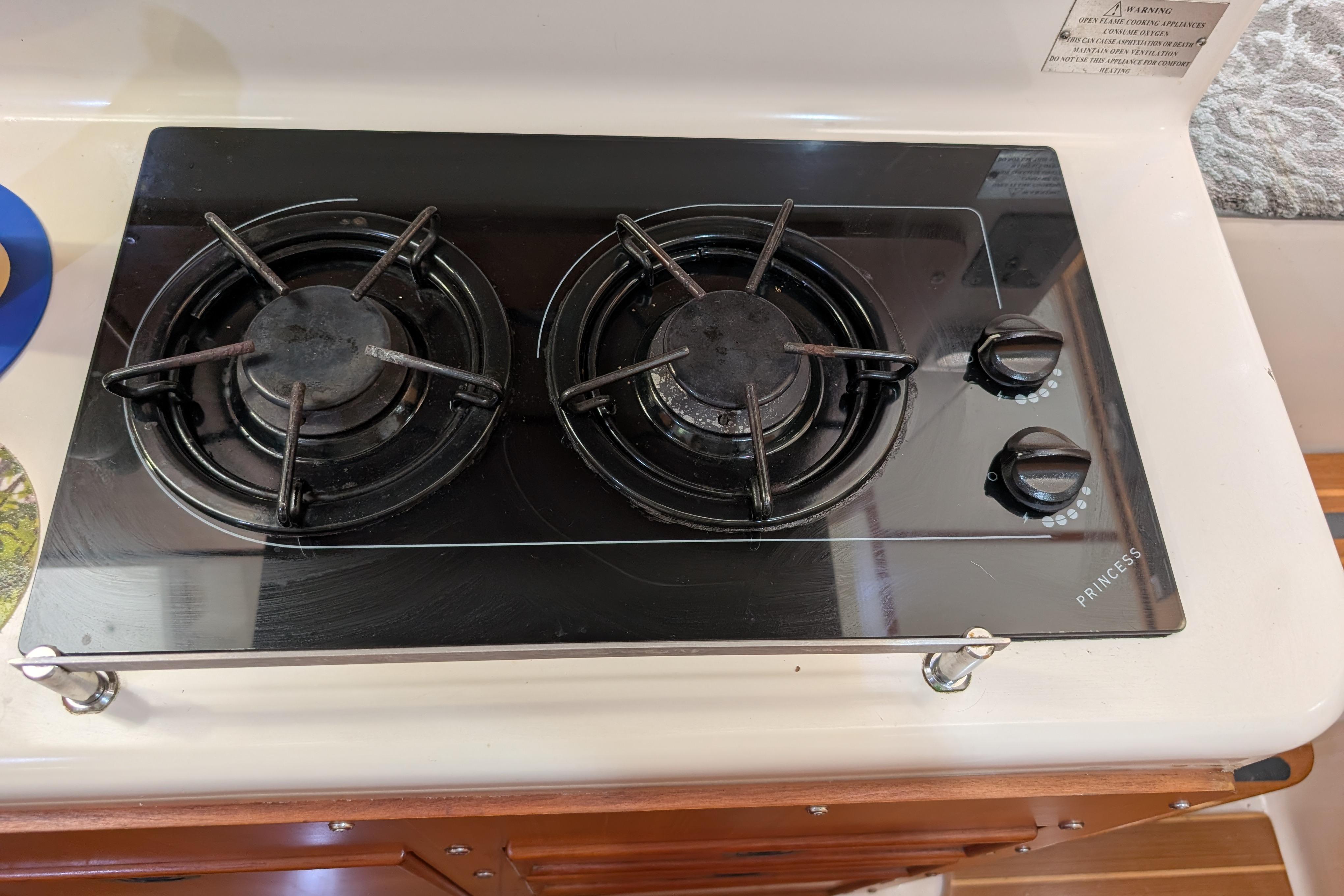 Two-burner stove on 2004 PDQ 34 Powercat boat, featuring black glass surface and control knobs.