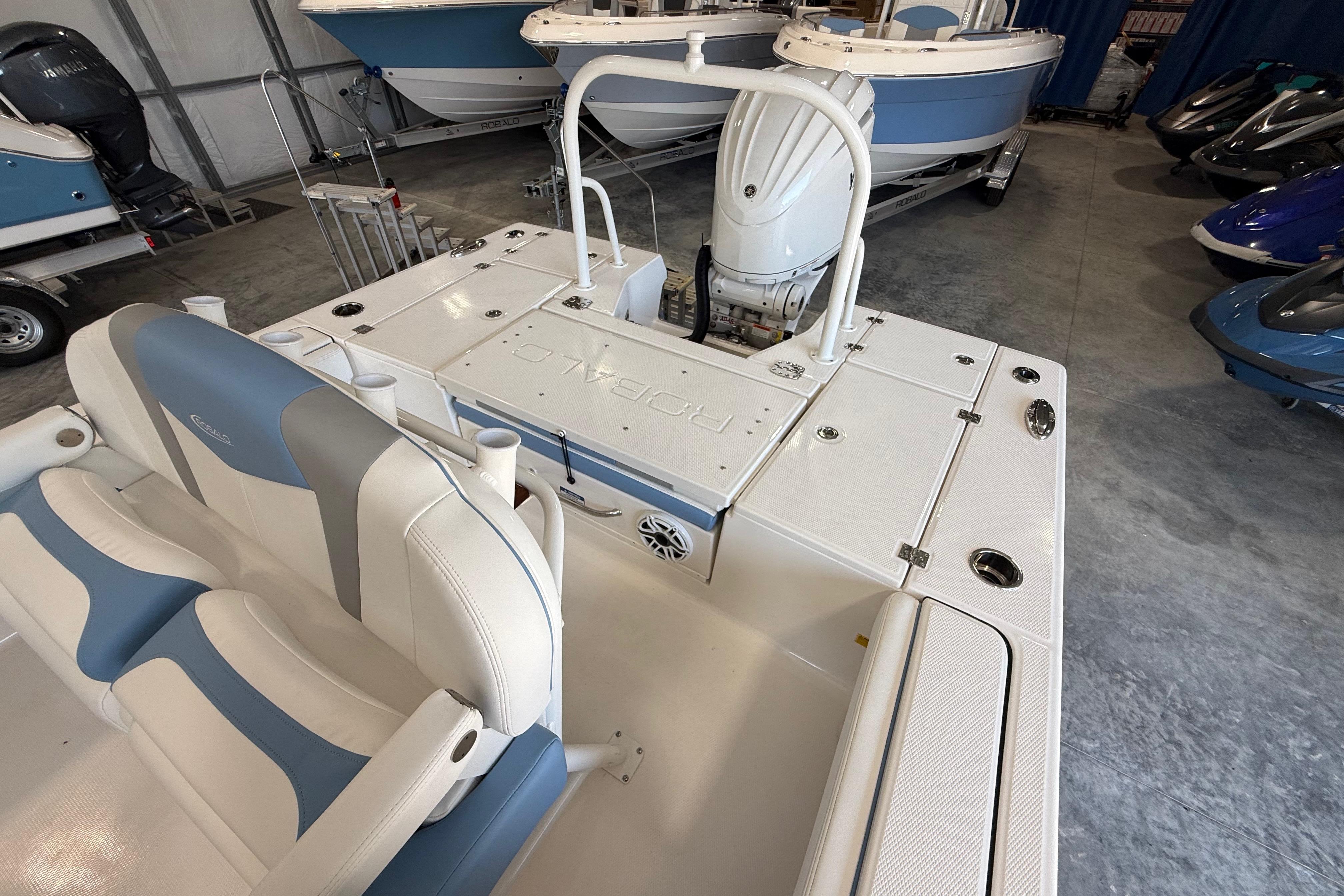 2026 Robalo 246 Cayman boat interior with seating and engine in showroom.