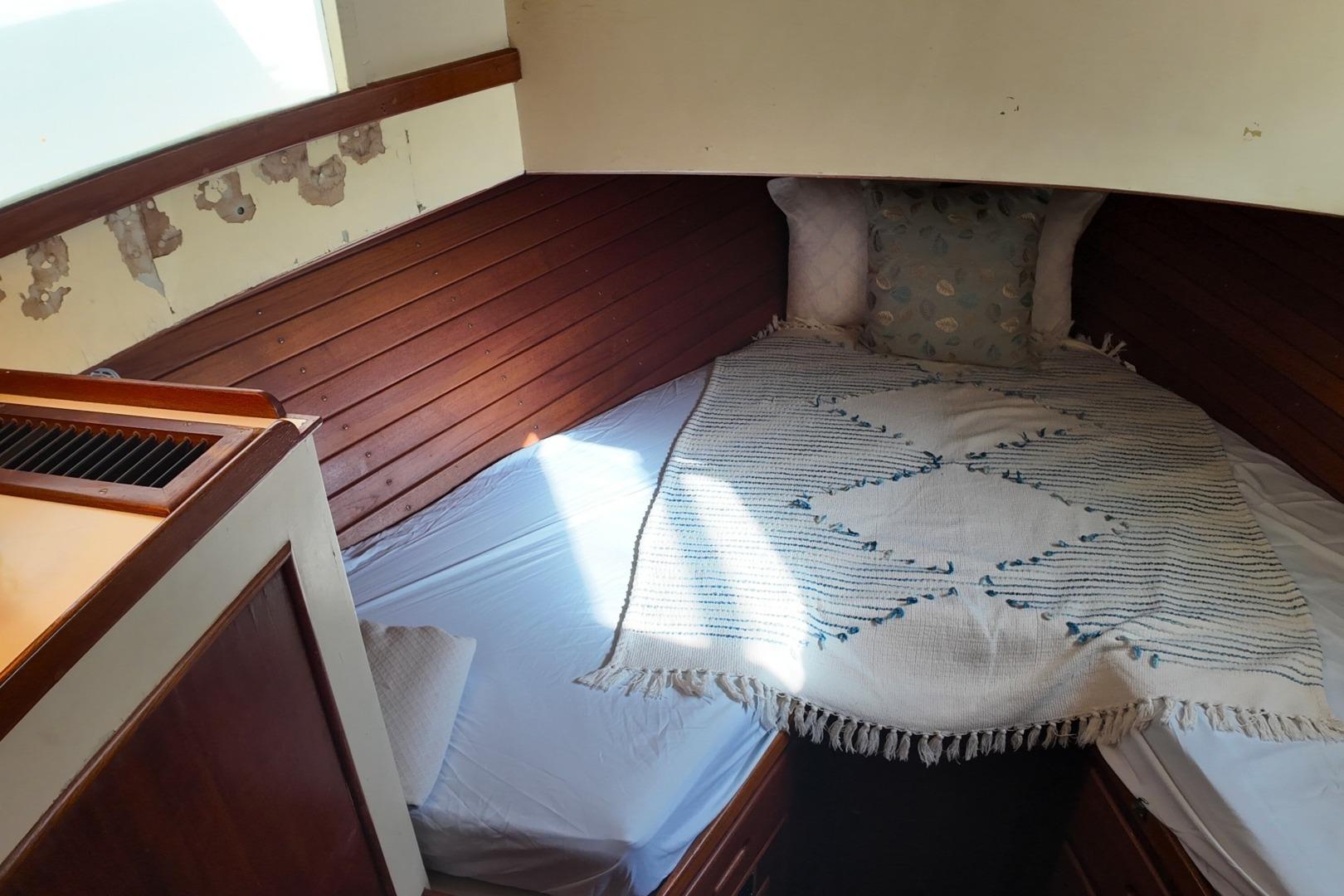 Cozy cabin interior of 1978 Grand Banks 42 Classic yacht with wooden paneling and bedding.