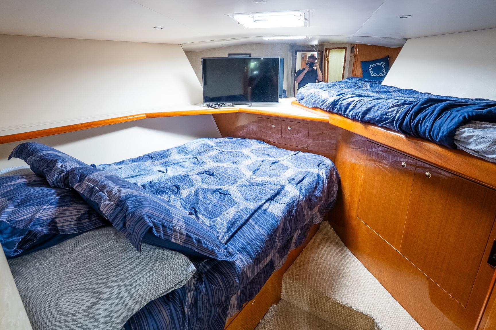 Cozy cabin interior of 2002 Viking 61 Enclosed Bridge yacht with blue bedding.