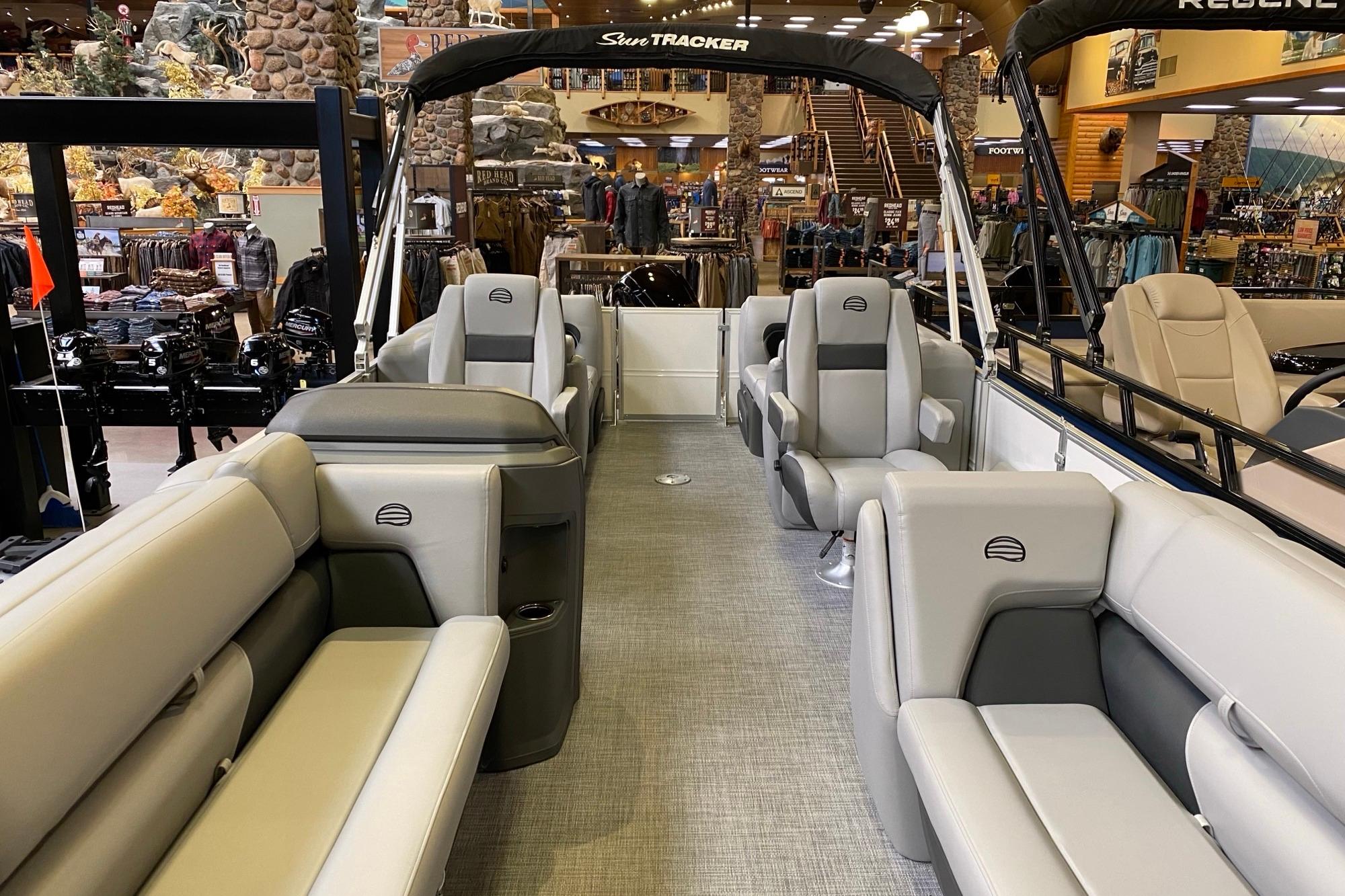 2026 Sun Tracker Party Barge 22 DLX pontoon boat interior with plush seating in showroom.