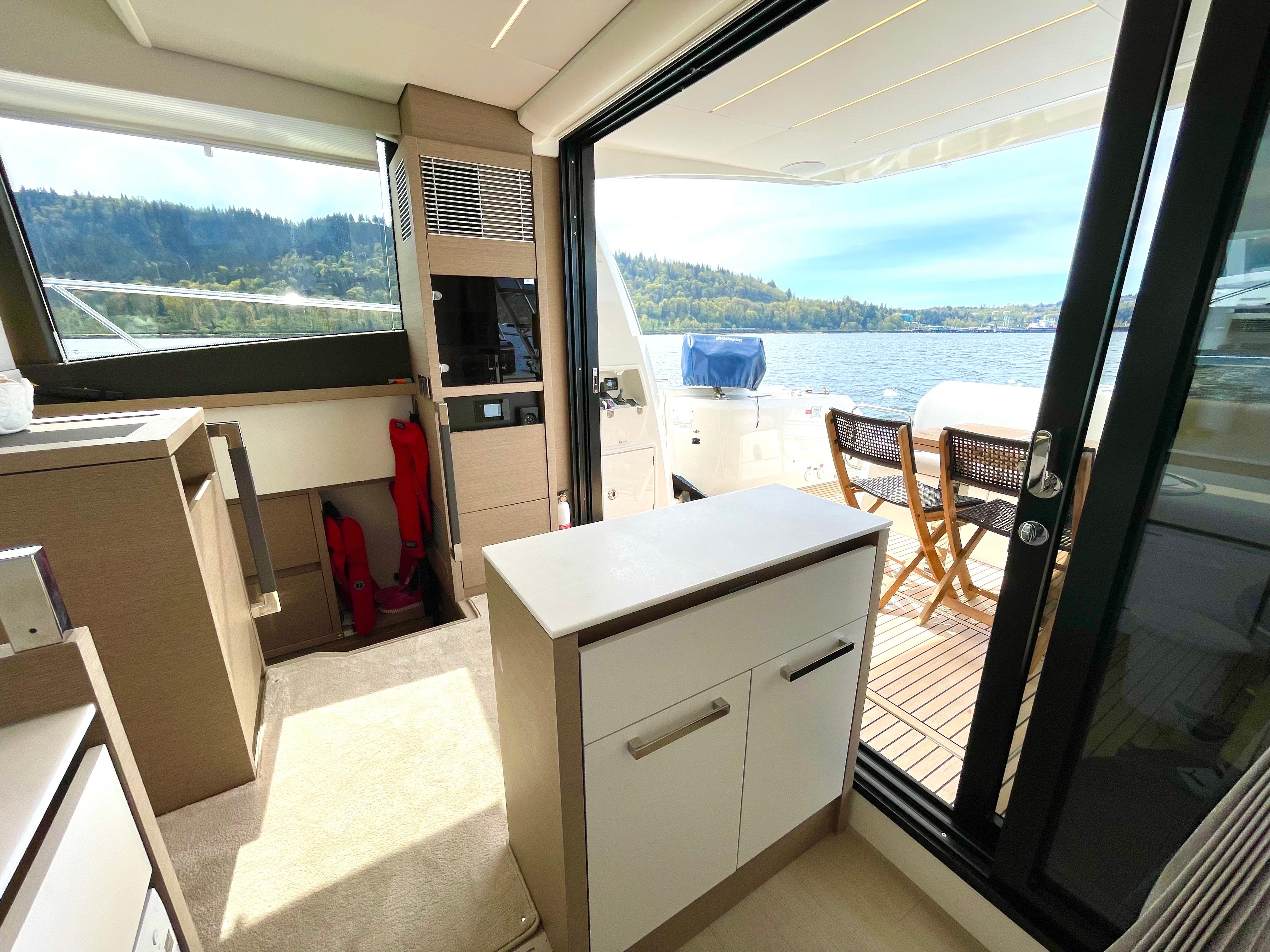 Modern interior of 2023 Prestige 520 yacht with outdoor seating and scenic water view.