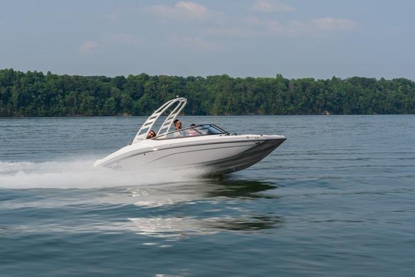 2026 Yamaha Boats 195S speeding on a lake with lush green forest backdrop.
