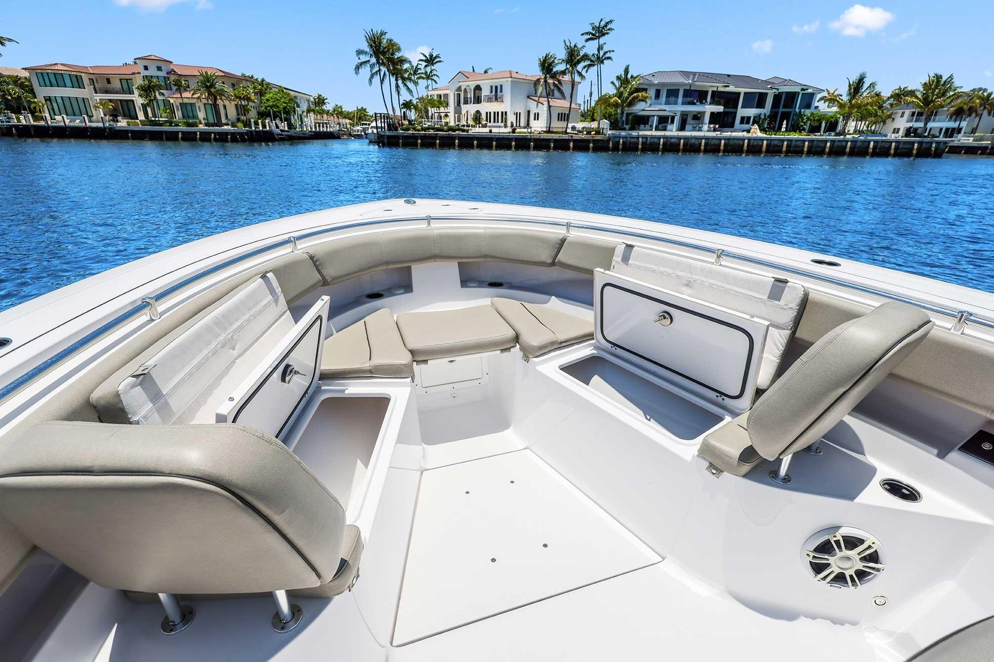2024 Sportsman Open 352 Center Console boat interior with seating and storage, docked by waterfront homes.