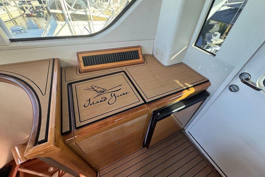 Interior of 2002 Viking 61 Enclosed Bridge yacht with wooden cabinetry and "Island Yacht" logo.