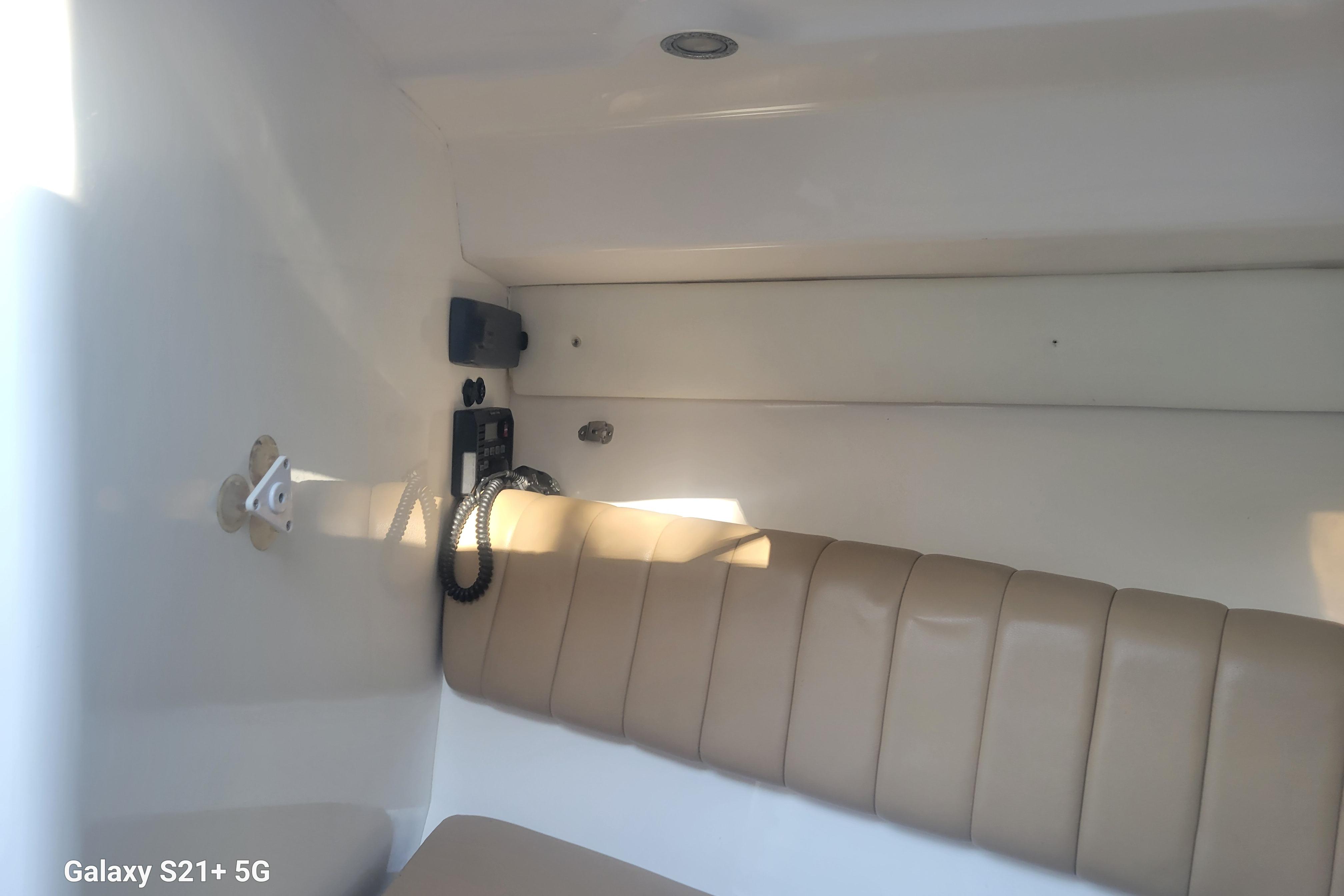 Interior of 2005 Intrepid 323 Cuddy, featuring beige seating and communication equipment.
